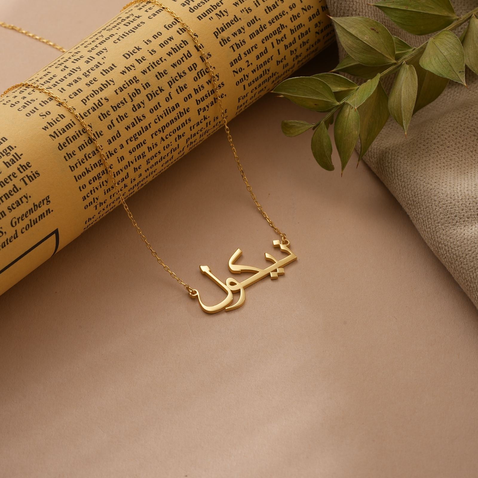 Personalized Arabic Name Necklace displayed on a vintage background with greenery, crafted in gold vermeil.
