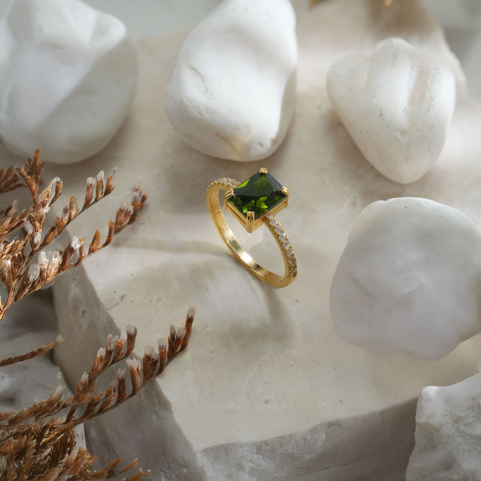 Rectangle Statement Birthstone Ring featuring a green birthstone set in gold on a stone backdrop.