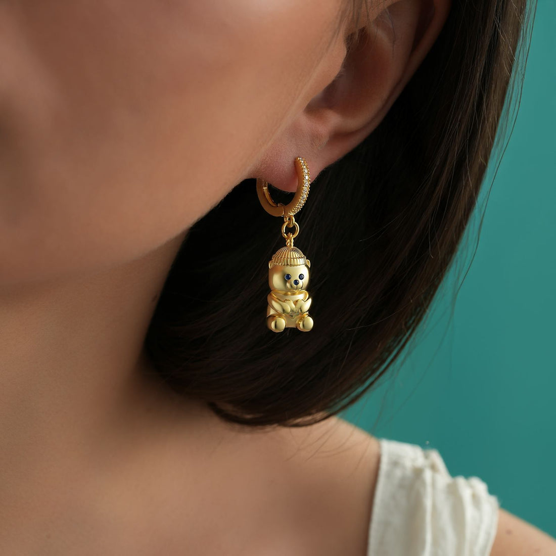 Gold Filled Bear Earrings worn on model's ear against a teal background