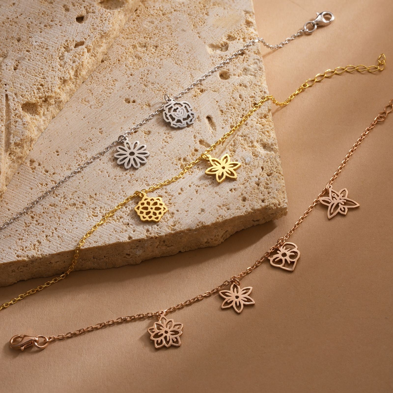 Custom Birth Flower Bracelet showcasing silver and gold flower charms on a textured stone background.