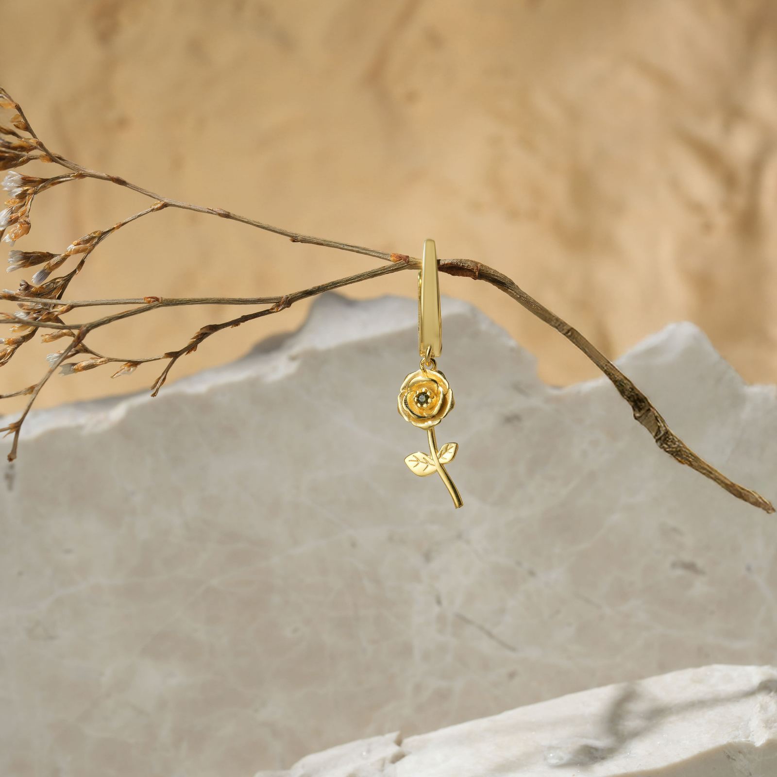 Birth Flower Hoop Earring crafted in gold vermeil, featuring a delicate rose and leaf design, set against a natural backdrop.