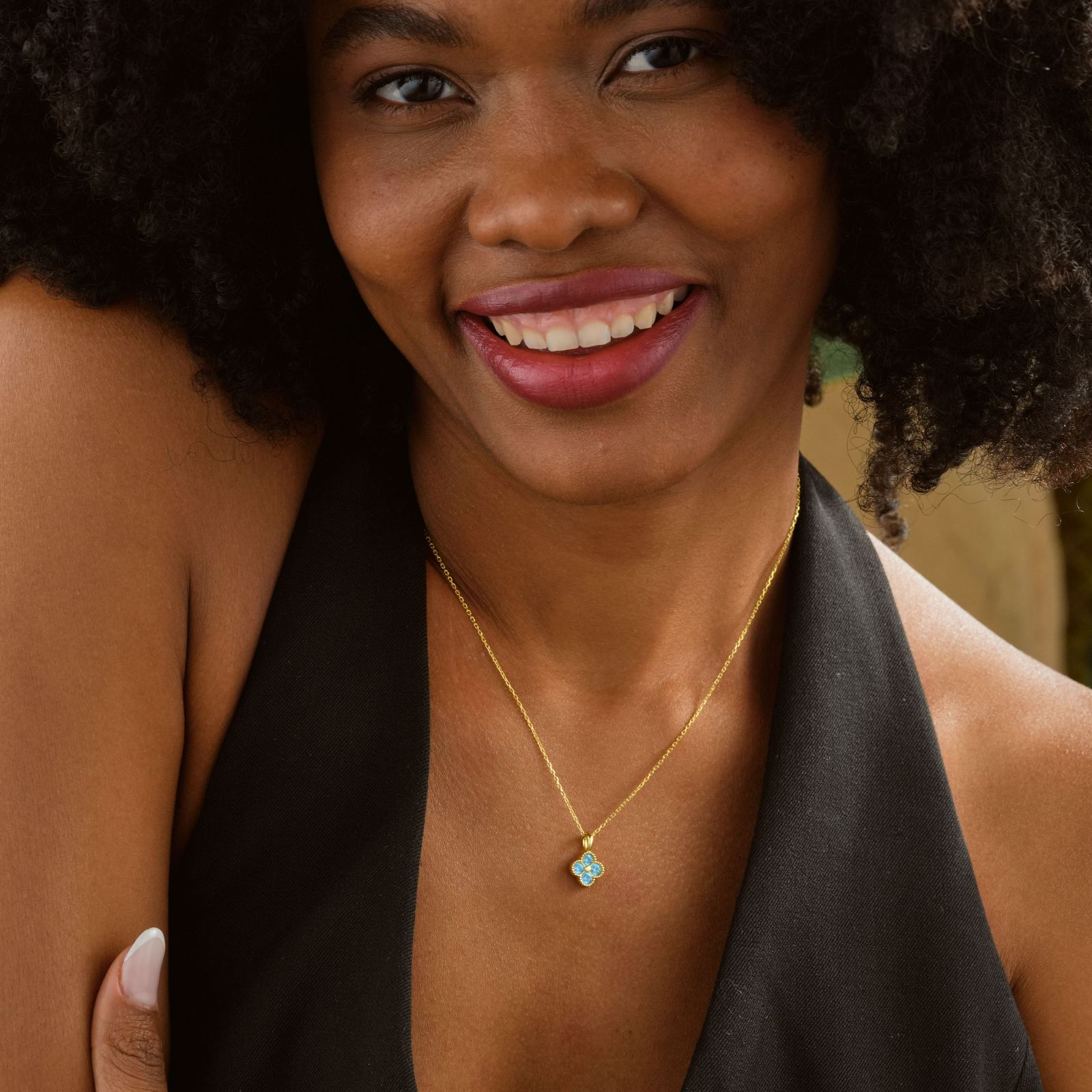 Elegant Clover Birthstone Necklace worn by a smiling woman with curly hair and a black top.