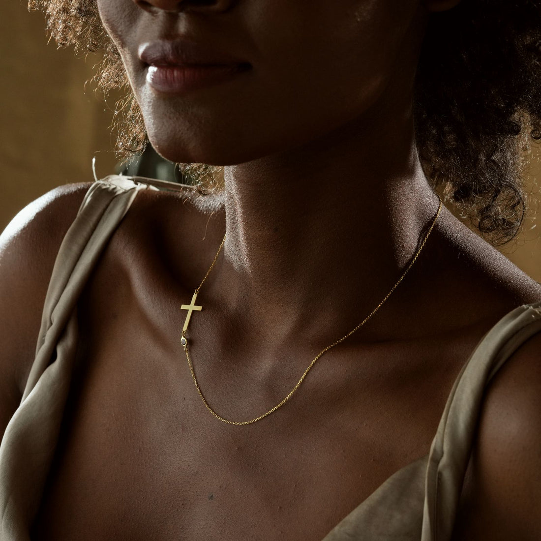 Close-up of a woman wearing a 14K Gold Filled Birthstone Cross Necklace, showcasing elegance and style.