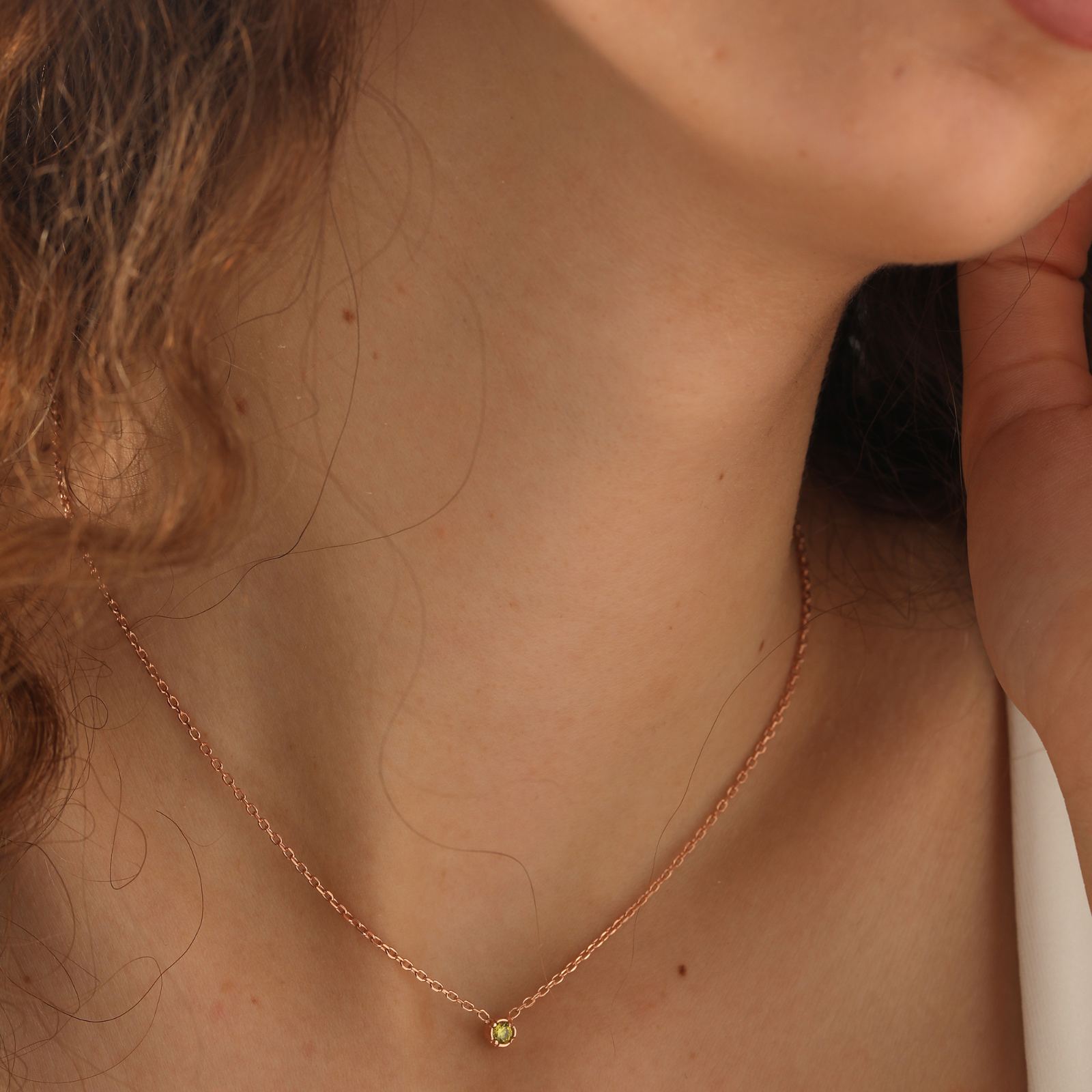 Close-up of a woman wearing a Personalized Birthstone Necklace with a delicate gold chain and a sparkling gemstone.