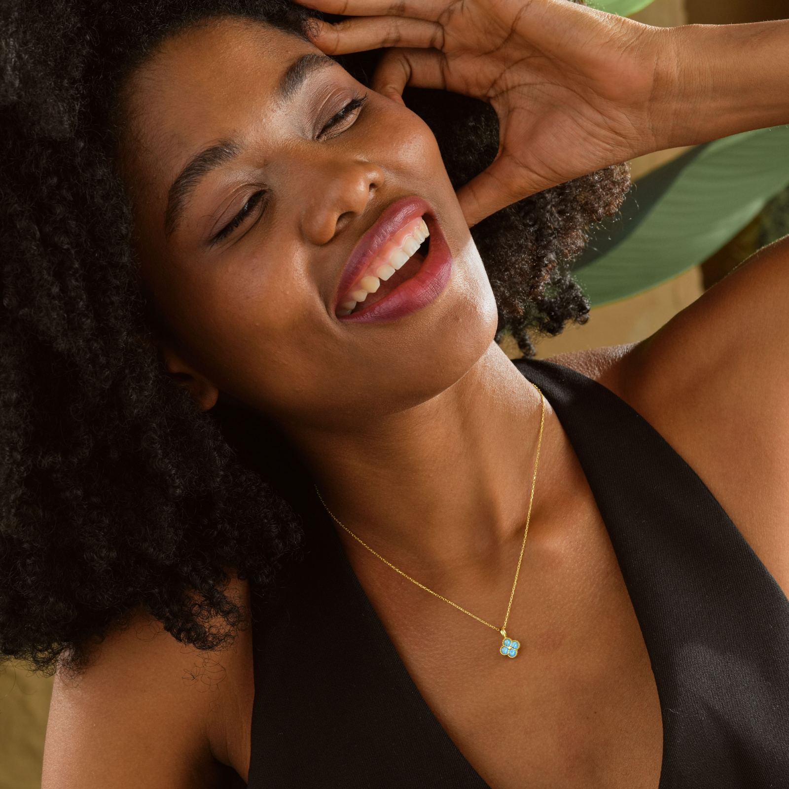 Woman wearing an Elegant Clover Birthstone Necklace with a turquoise stone, smiling and showcasing her stylish look.