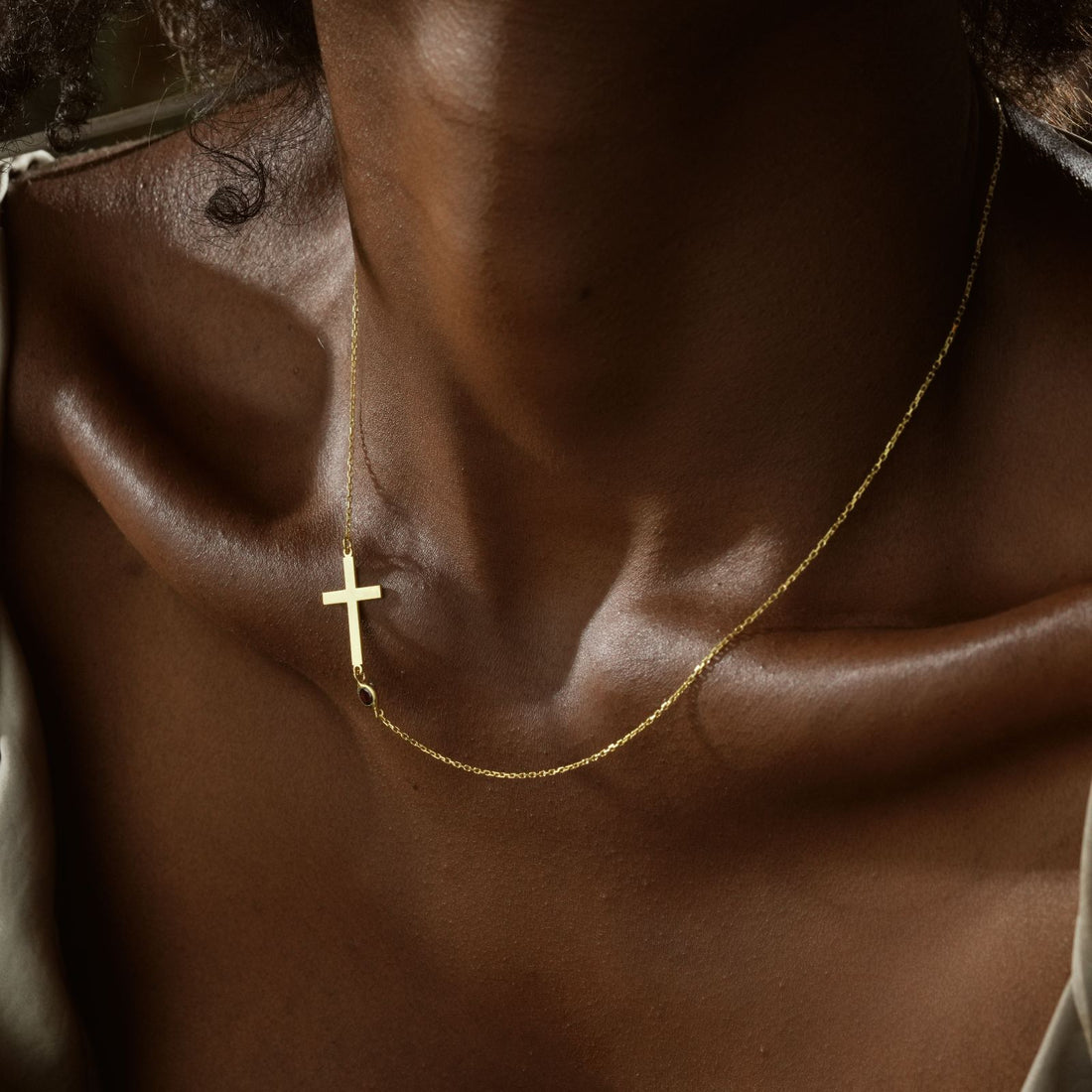 Close-up of a woman wearing a 14K Gold Filled Birthstone Cross Necklace, showcasing elegance and style.