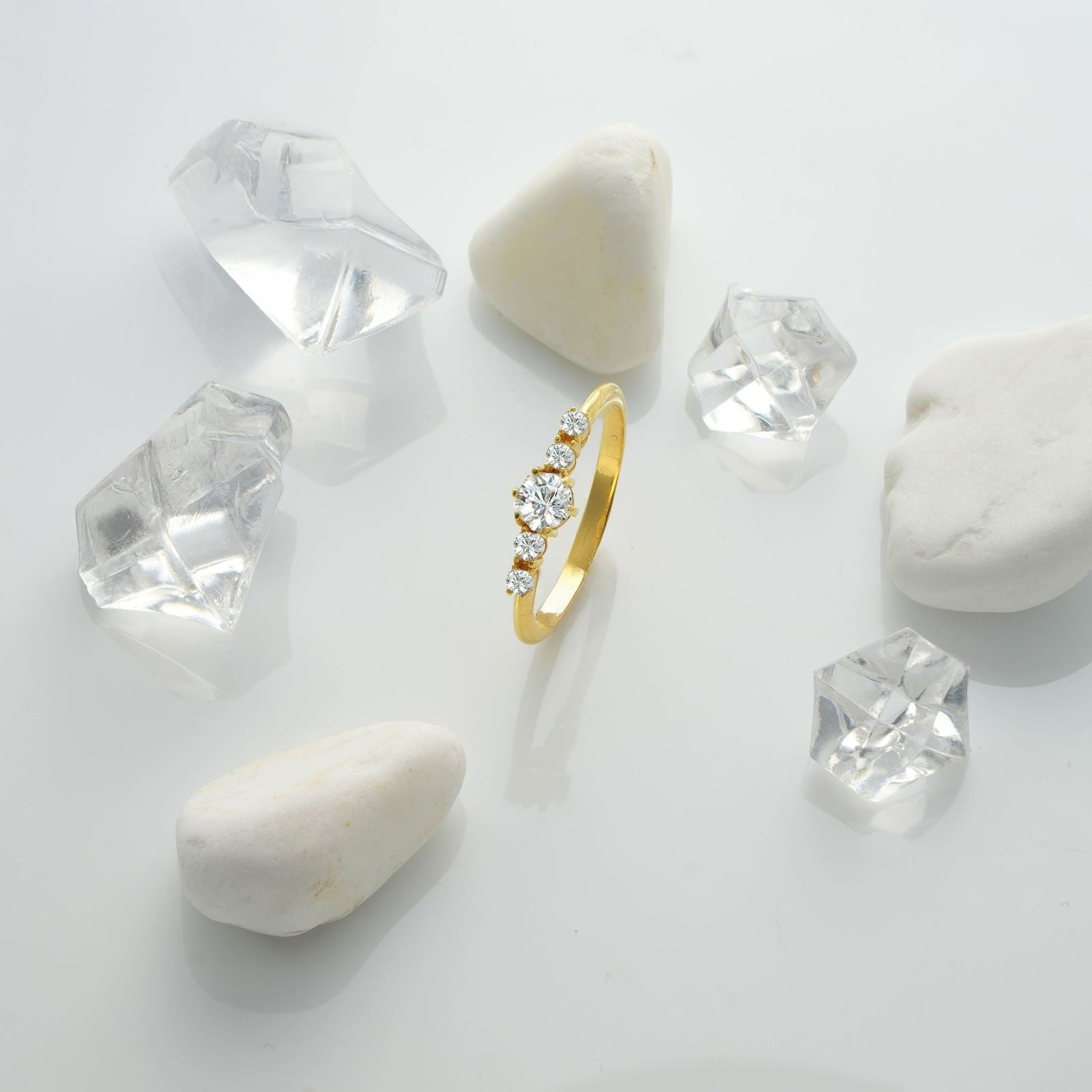 Round Cut Birthstone Ring surrounded by clear crystals on a white background, showcasing its elegance and shine.