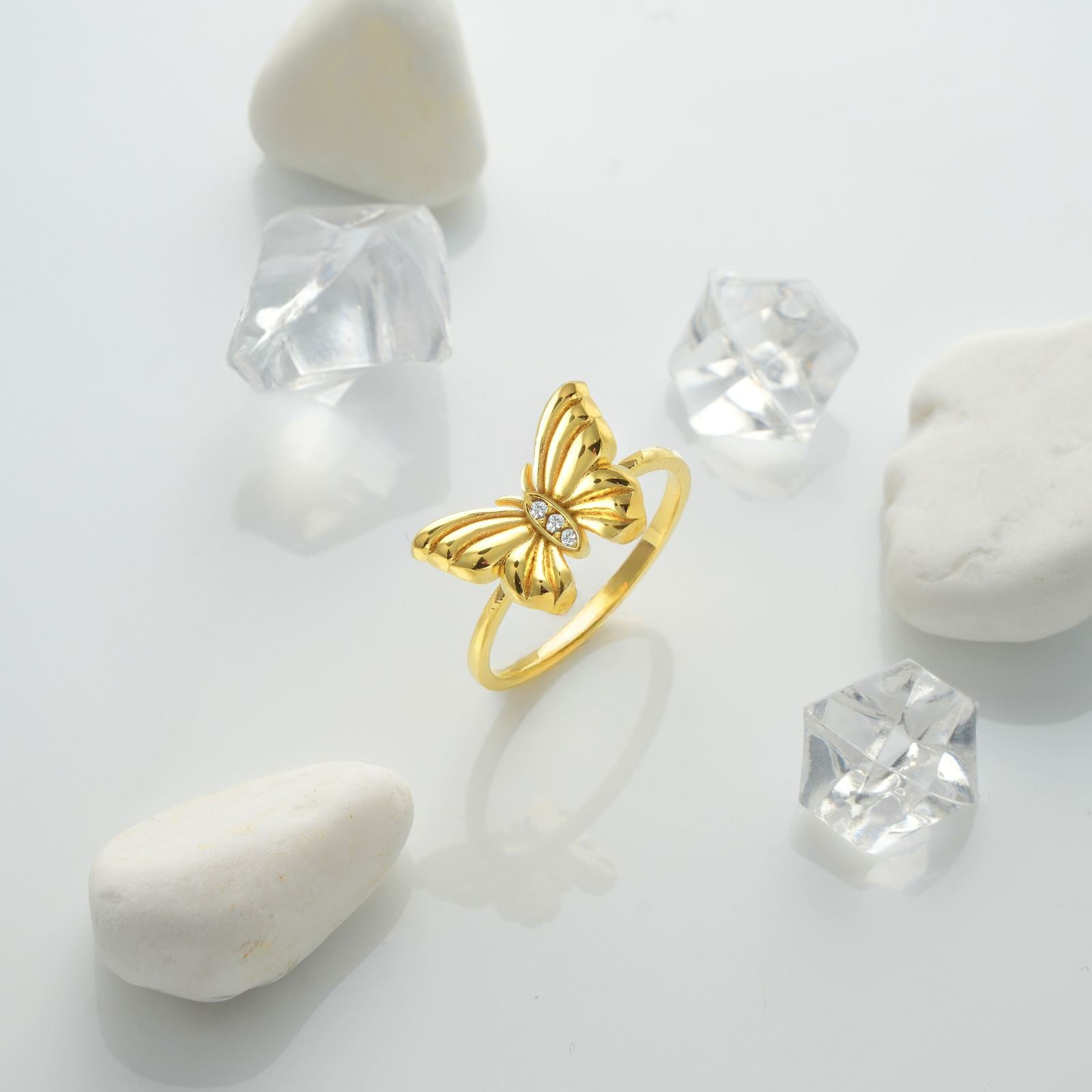 Dainty Butterfly Birthstone Ring beautifully showcased among clear crystals and smooth stones.