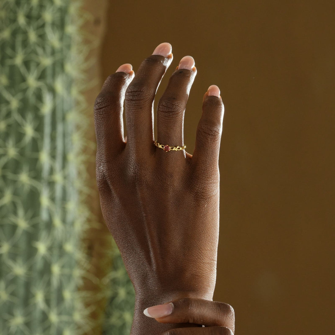 Nature-Inspired Floral Birthstone Ring displayed on a hand with soft manicure against a textured background.