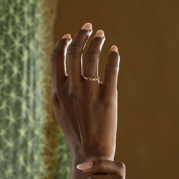 Nature-Inspired Floral Birthstone Ring displayed on a hand with soft manicure against a textured background.