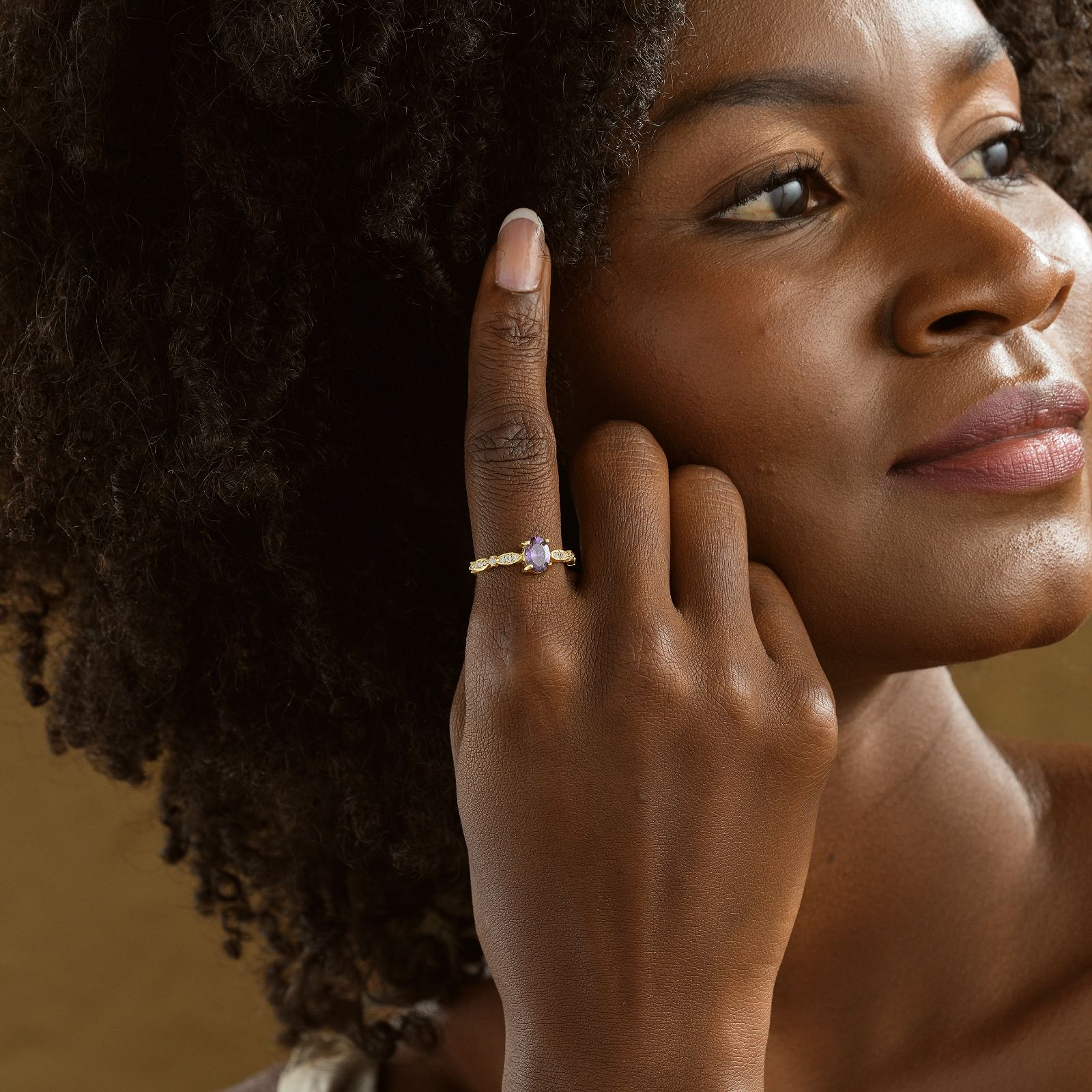 A woman showcasing a Custom Birthstone Ring on her finger, featuring colorful gemstones and elegant design.