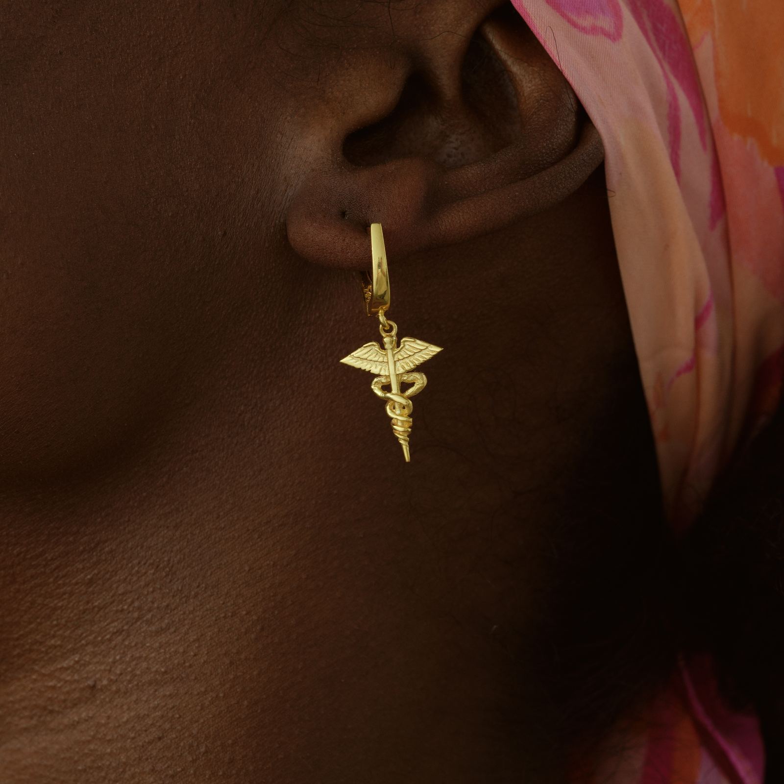 Caduceus Earring worn on ear, stylish hoop design, graduation gift option made of gold.