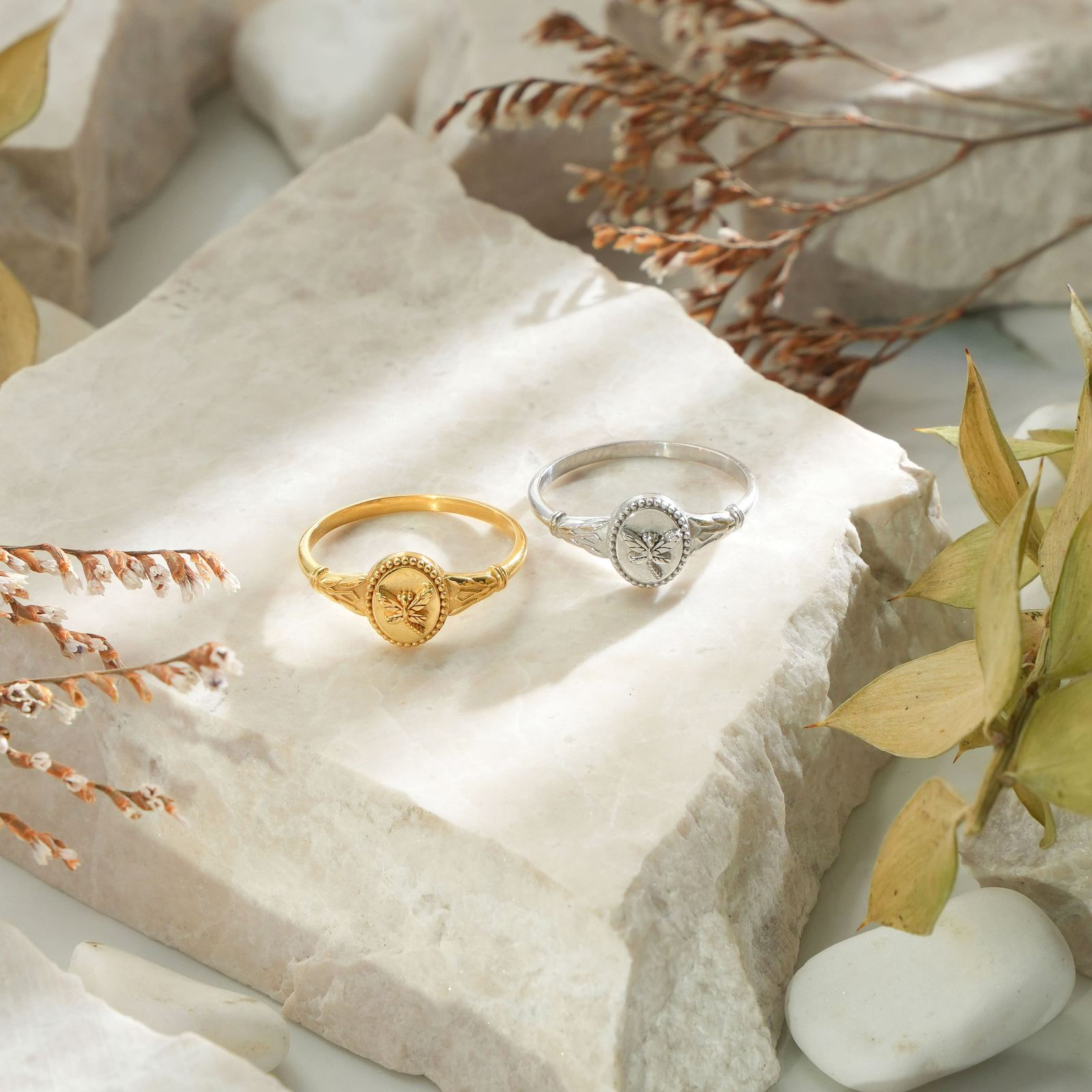 Dragonfly Pinky Ring for Women in gold vermeil and silver resting on natural stone with dried leaves.