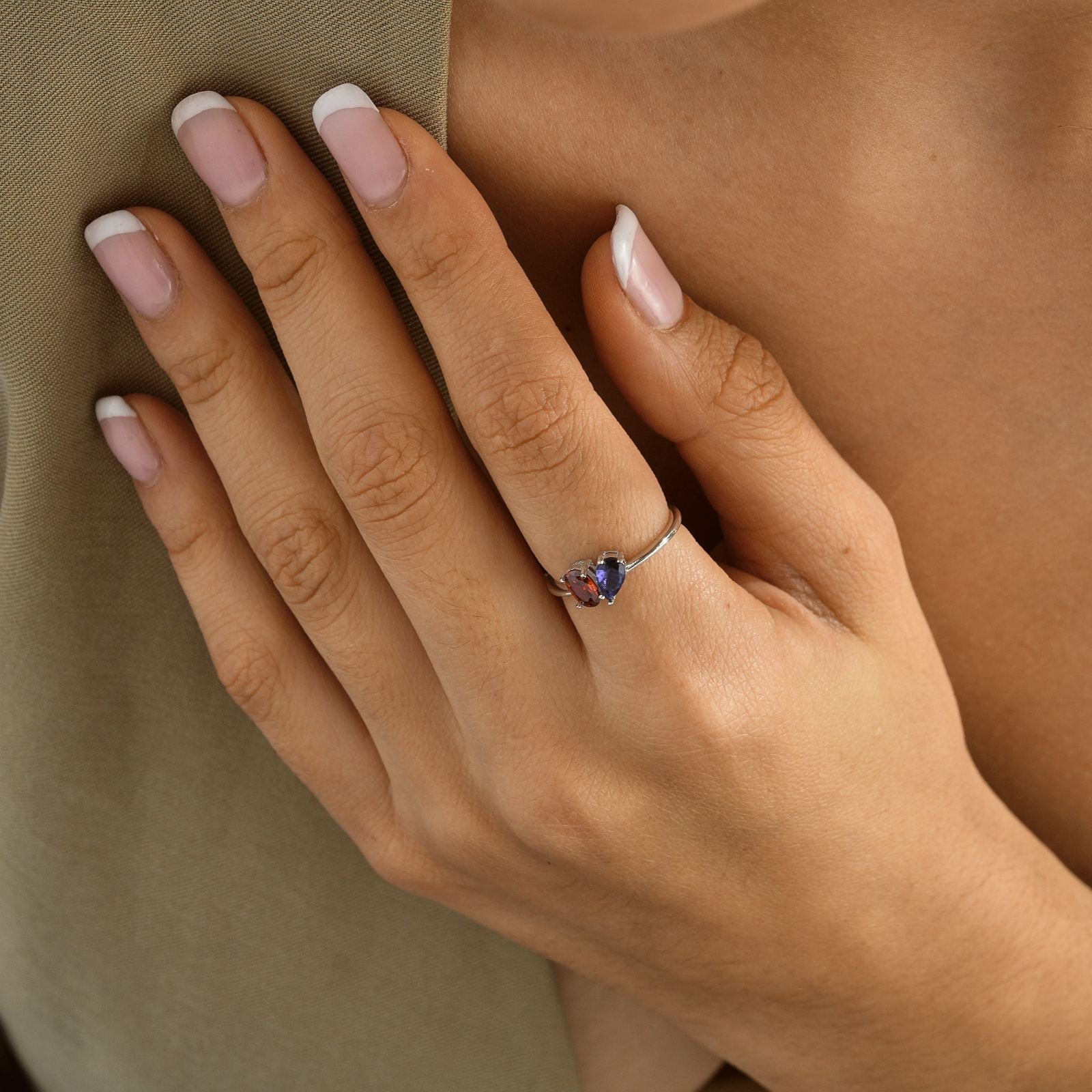 Hand wearing an Oval & Pear Cut Birthstone Ring in a close-up view, showcasing the ring's colorful gemstones.