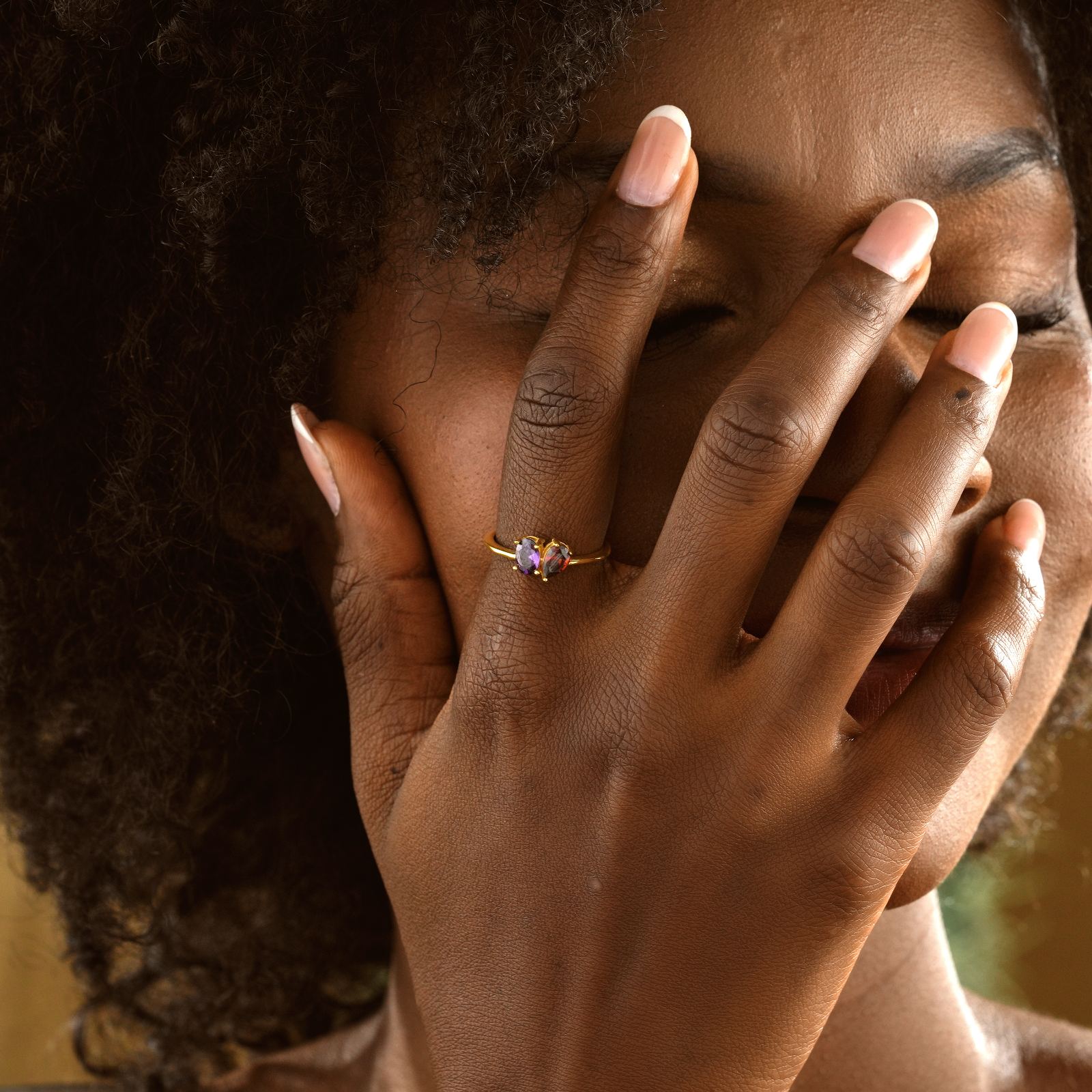 Woman wearing an Oval & Pear Cut Birthstone Ring while playfully covering her face.