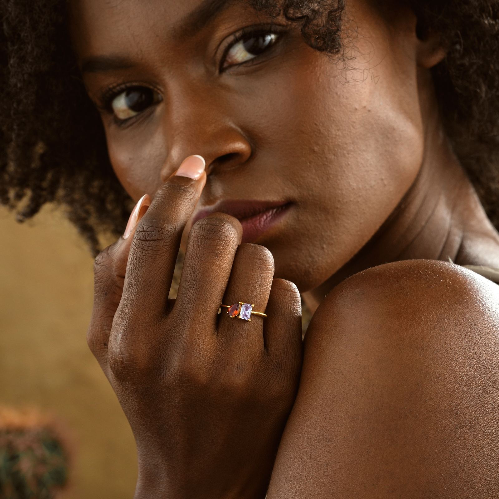 Close-up of a woman wearing an Oval & Emerald Cut Birthstone Ring on her finger, showcasing elegant jewelry craftsmanship.