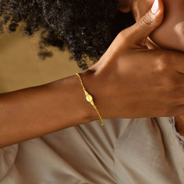 Engraved Oval Name Bracelet in sterling silver worn on a woman's wrist, styled with natural curls.