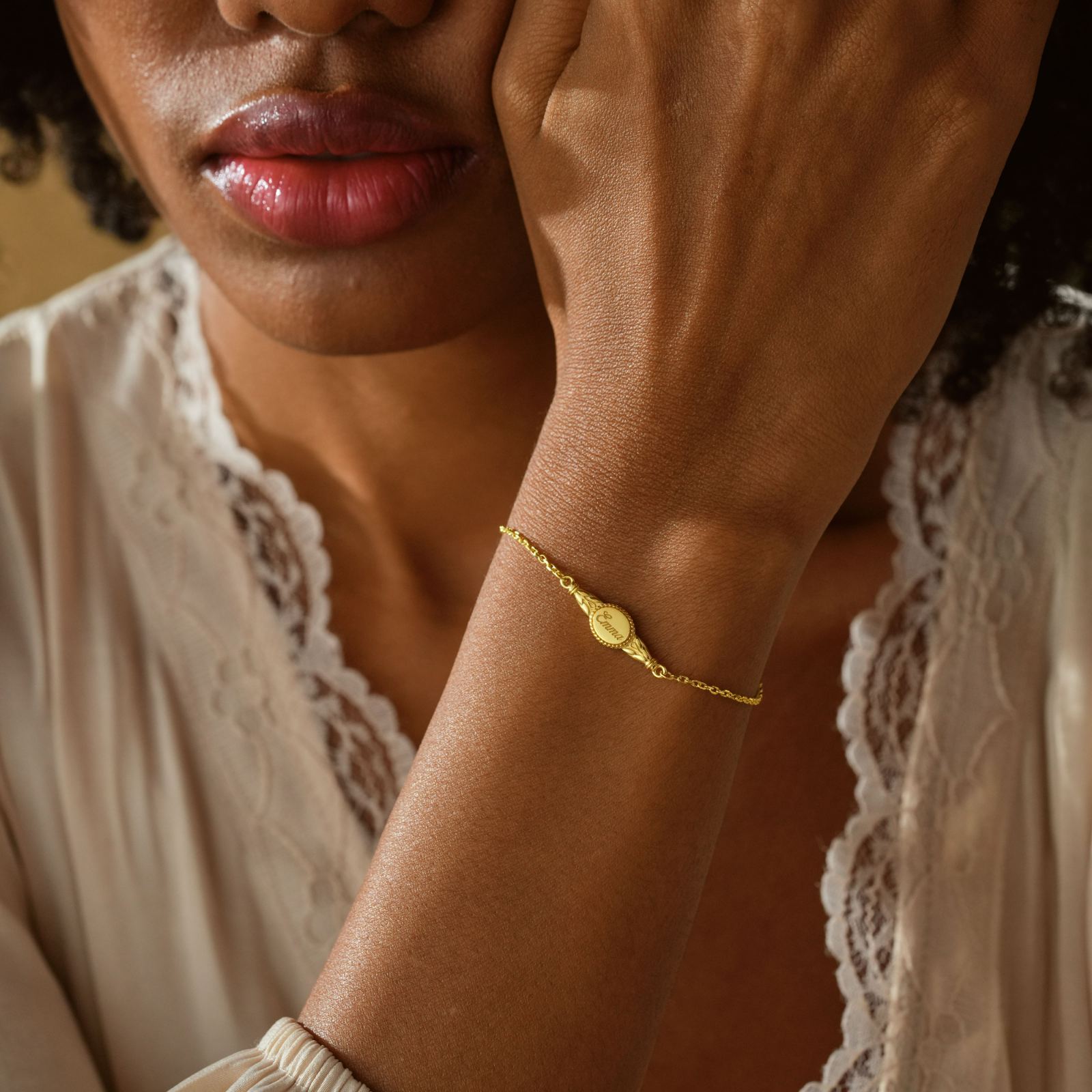 Close-up of a woman wearing an Engraved Oval Name Bracelet in gold on her wrist, showcasing the elegant design.