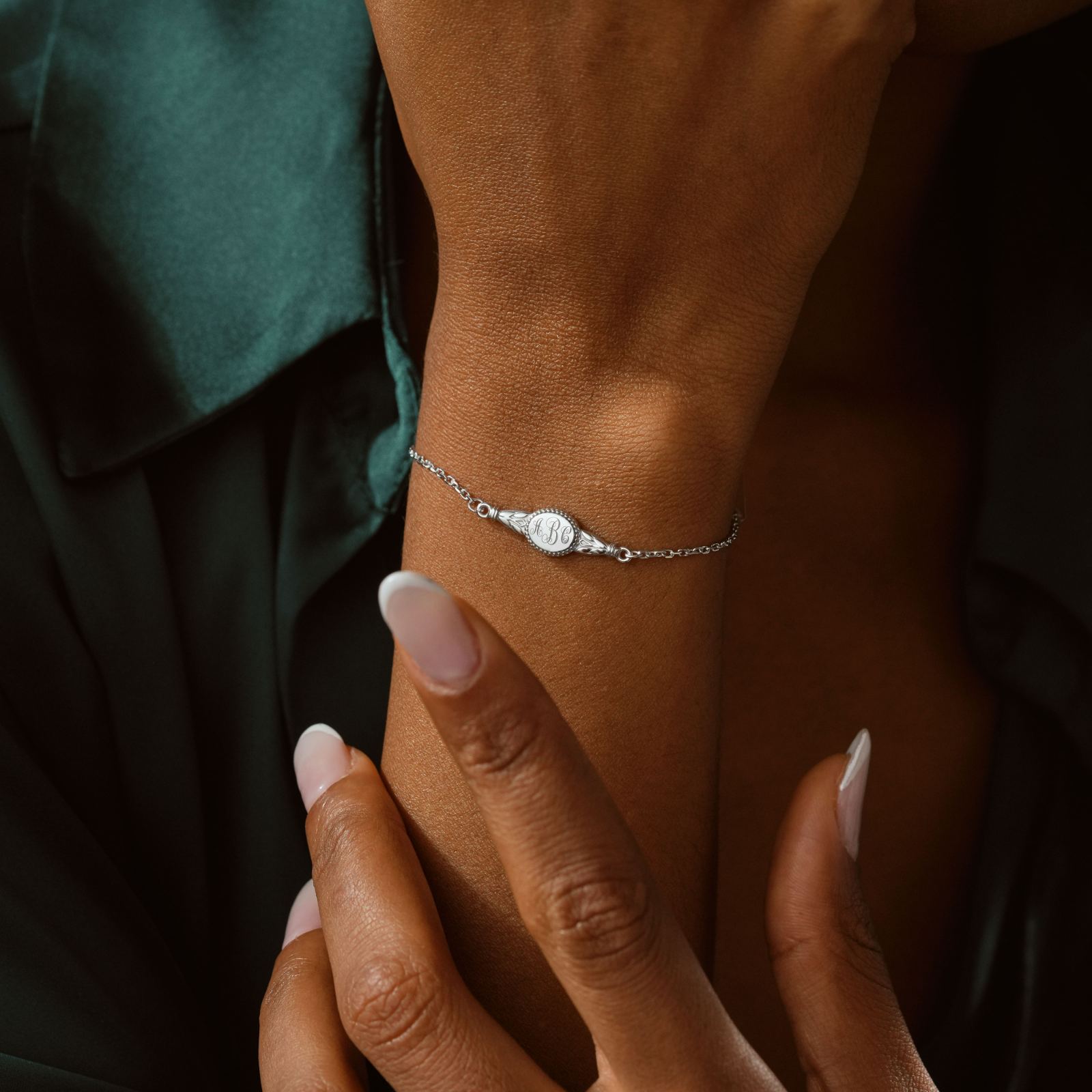 Engraved Oval Name Bracelet Sterling Silver worn on wrist with elegant hand gesture.