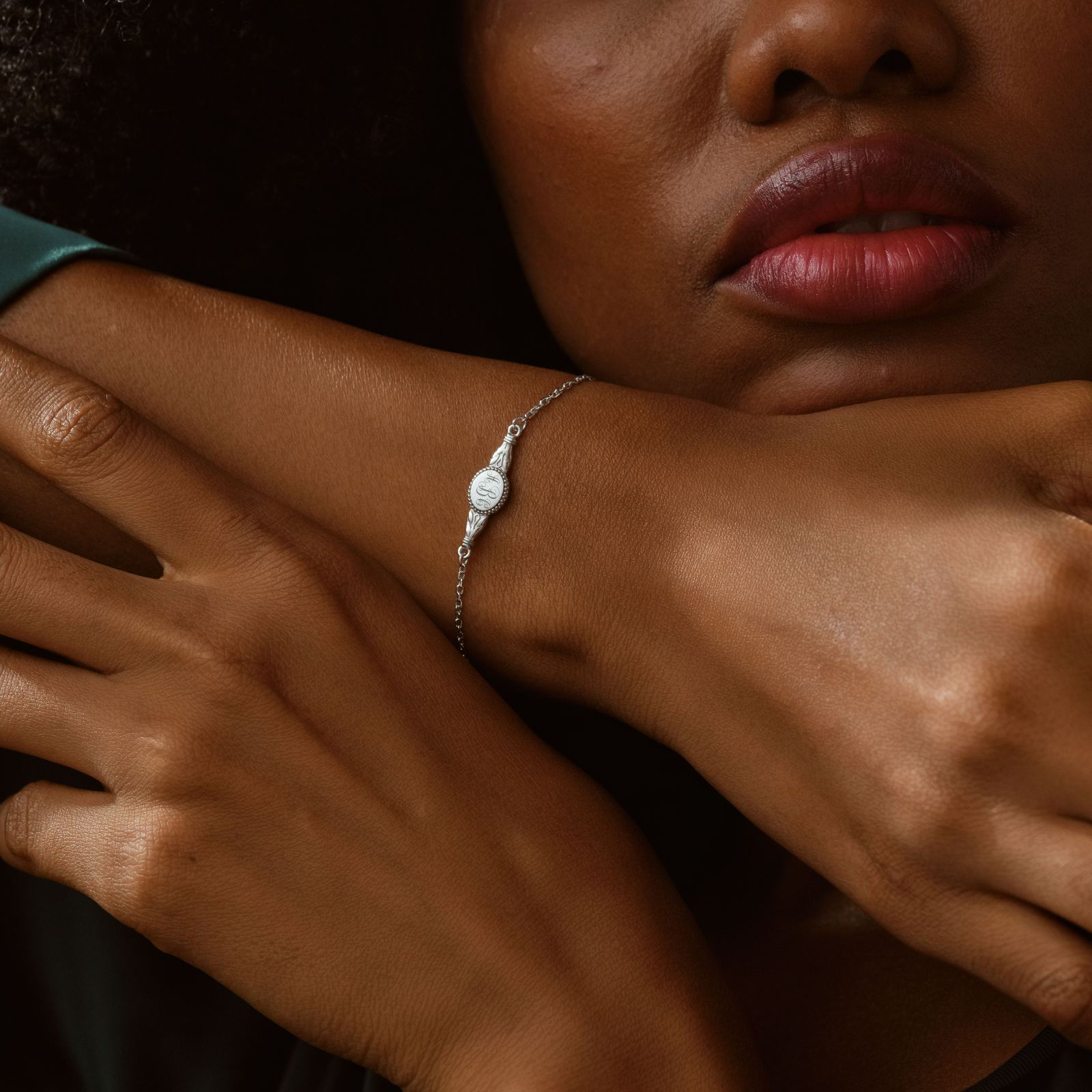 Engraved Oval Name Bracelet worn on a woman's wrist showcasing the delicate sterling silver design and personalized engraving.