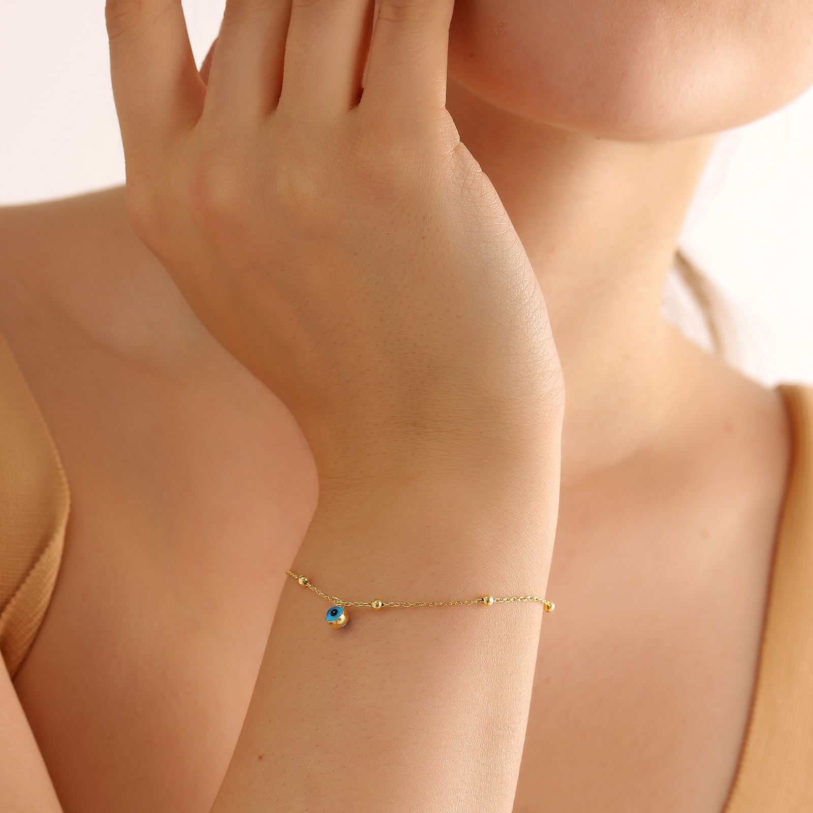 Charming Evil Eye Bracelet Sterling Silver worn on a woman's wrist, featuring a blue evil eye charm.