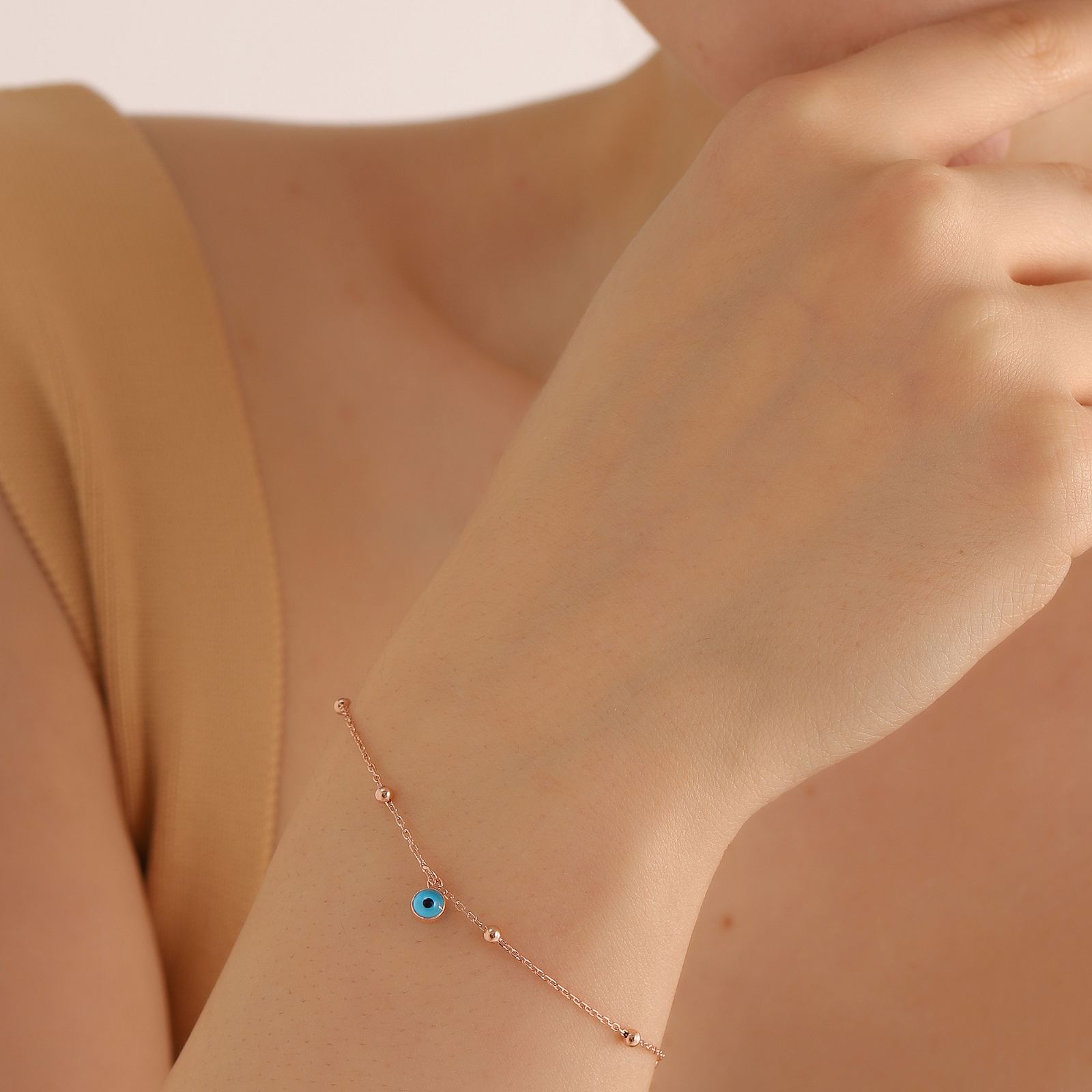 Charming Evil Eye Bracelet on a woman's wrist in rose gold vermeil, featuring a blue evil eye gemstone.