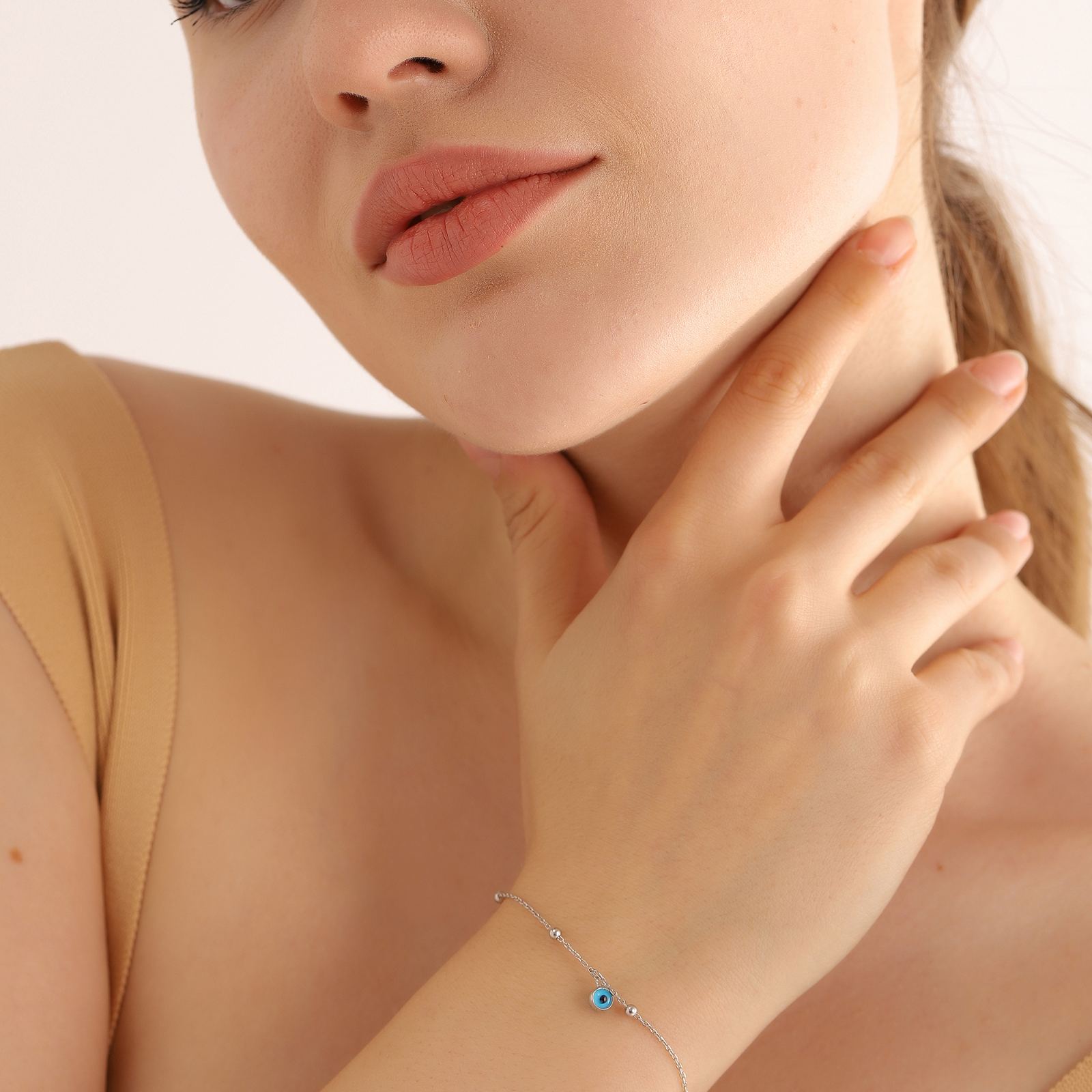 Close-up of a woman wearing a Charming Evil Eye Bracelet made of sterling silver with a blue gemstone.