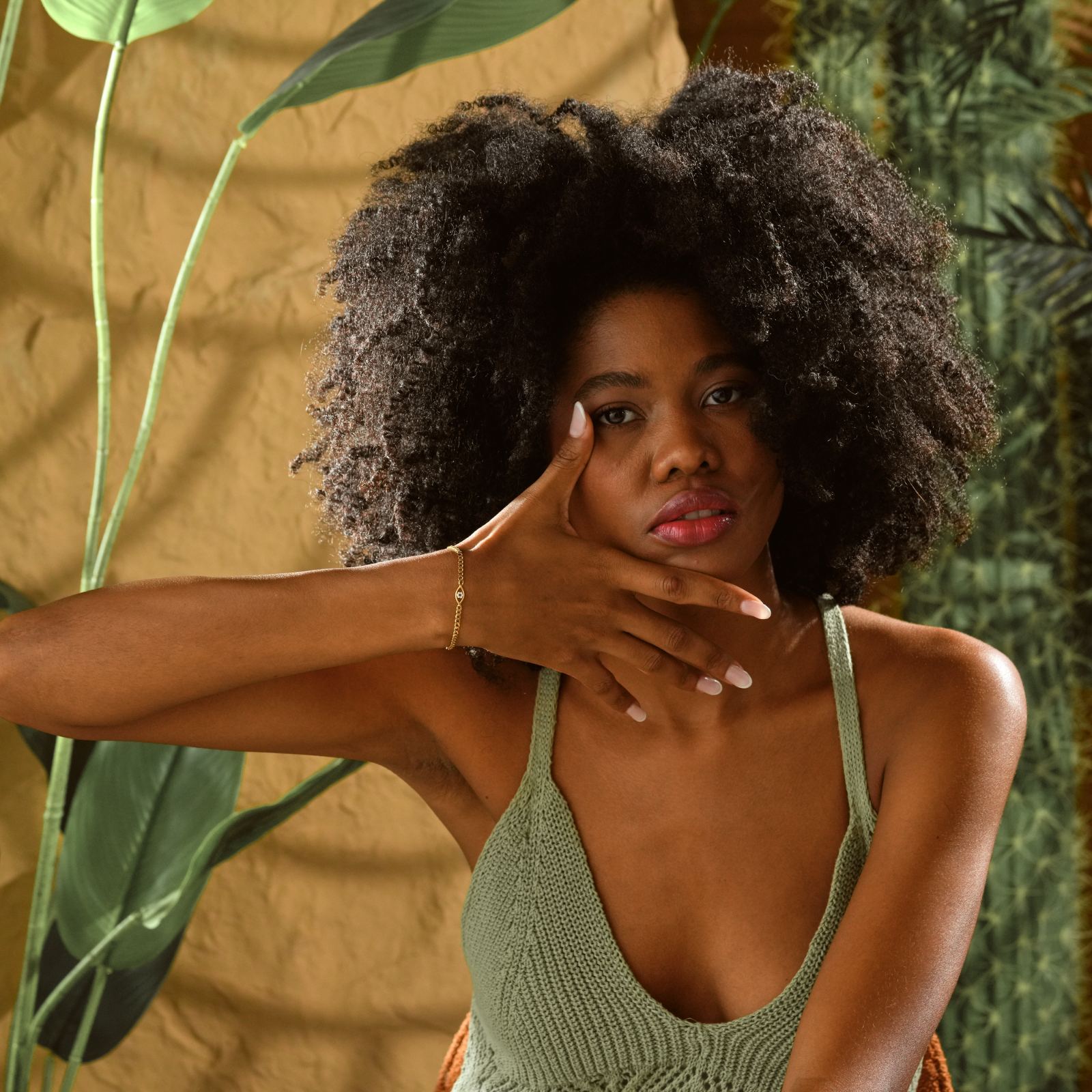 Evil Eye Curb Chain Bracelet showcased on model with curly hair, wearing a green top against a botanical background.