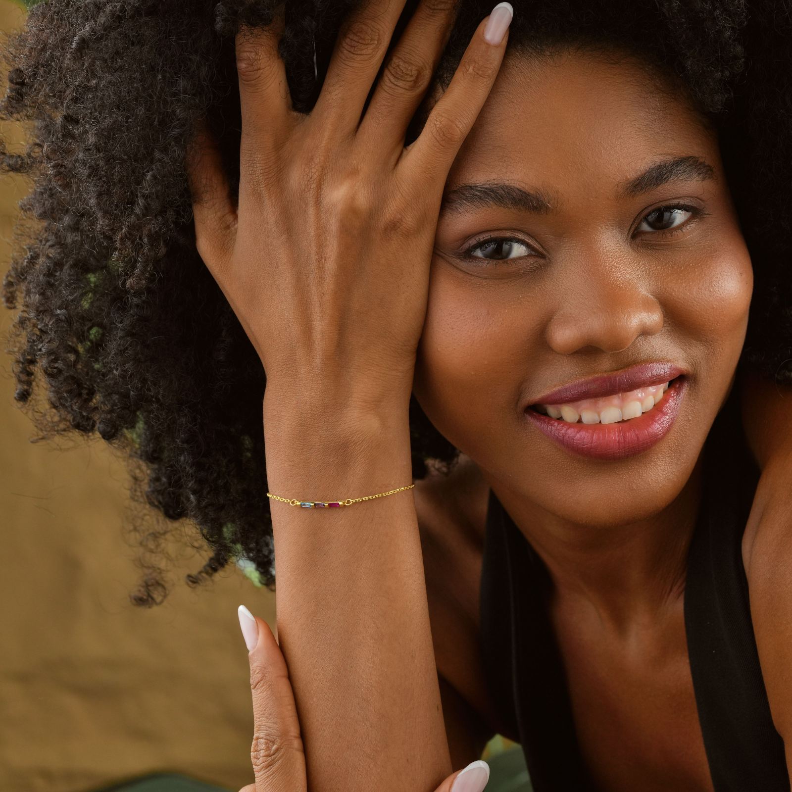 Elegant Gold Filled Birthstone Bracelet worn by a smiling woman with curly hair, featuring colorful gems.