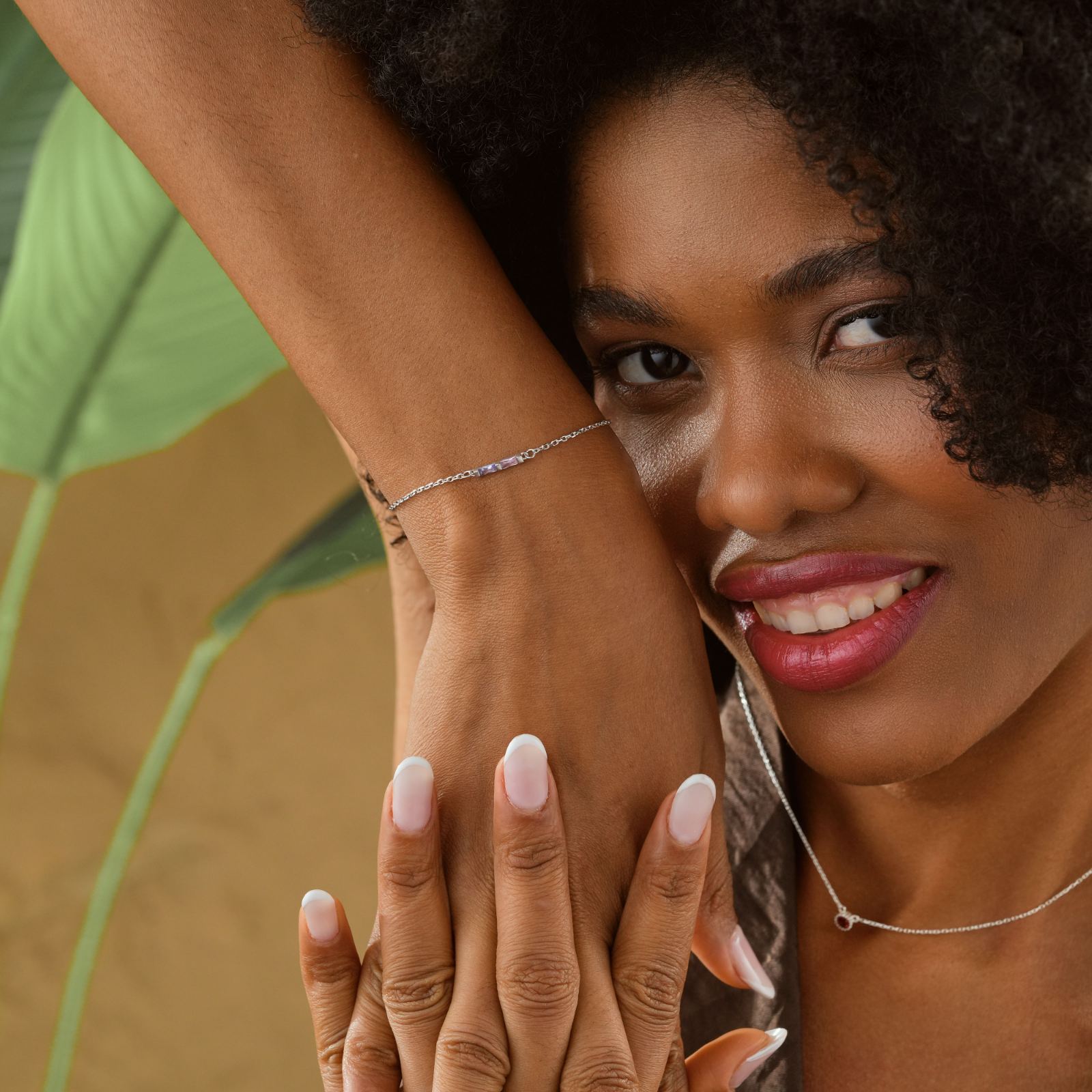 Elegant Gold Filled Birthstone Bracelet worn by a woman with curly hair, smiling and showing off her bracelet.