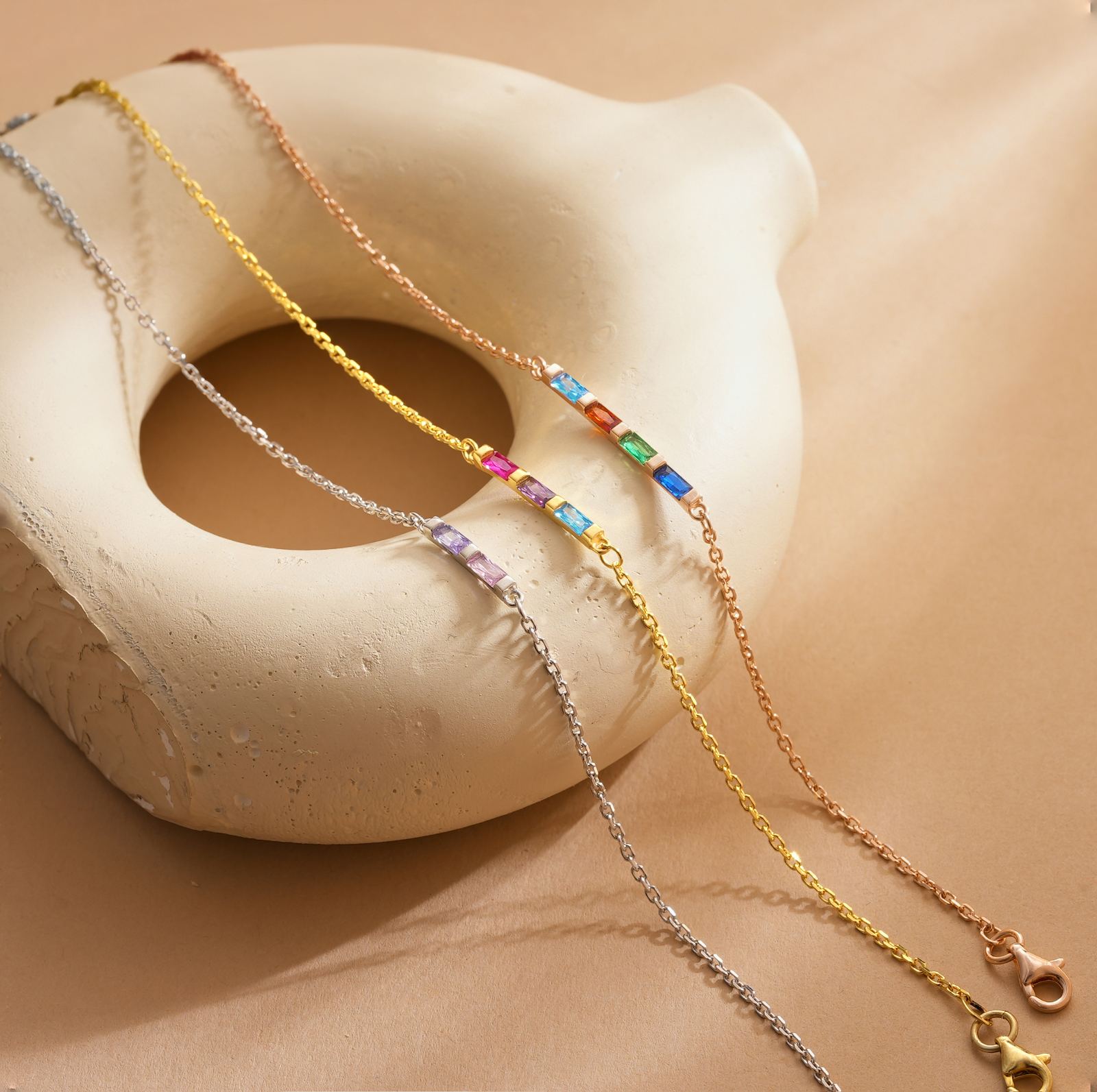Elegant Gold Filled Birthstone Bracelet displayed on a decorative surface with colorful stones.