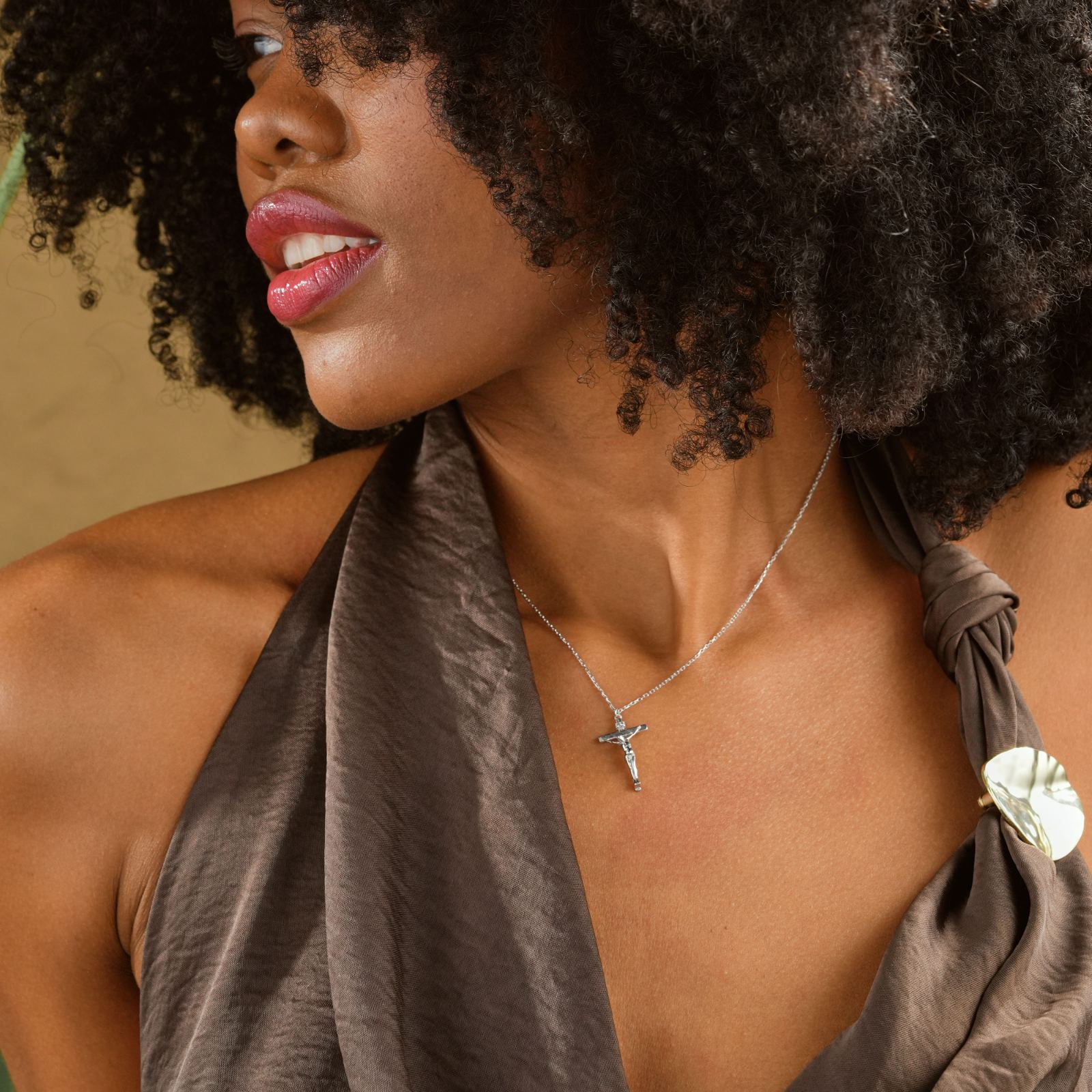 Gold Filled Crucifix Necklace worn by a woman with curly hair, showcasing its elegant design.