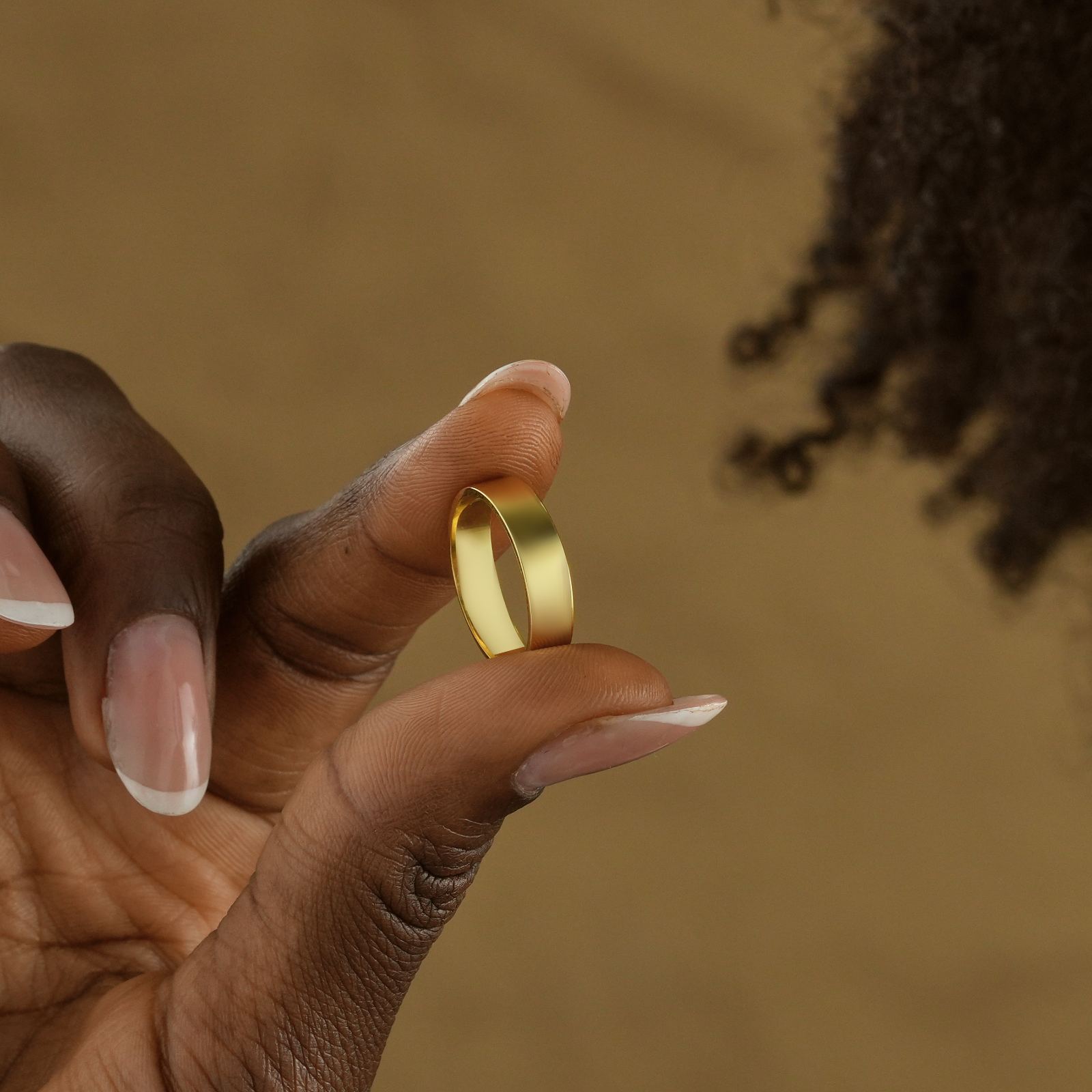 Thin Wedding Band Minimalist Stacking Ring held between fingers, showcasing its gold vermeil design.