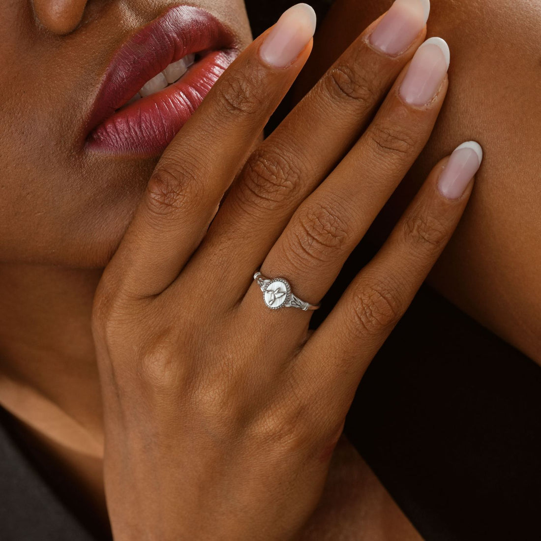 Hummingbird Signet Pinky Ring Sterling Silver worn on a model's hand with elegant nails and soft curls.