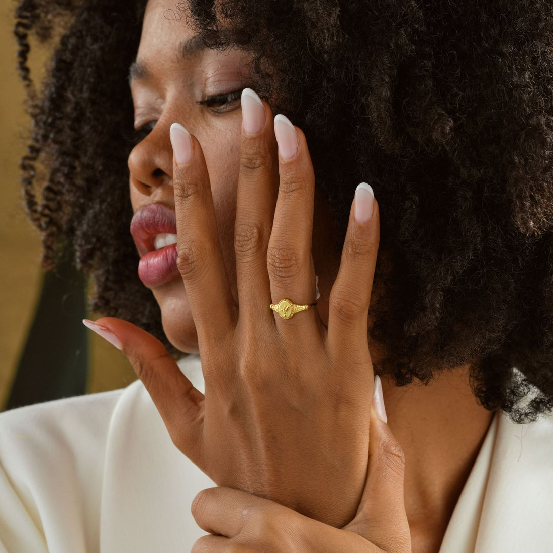 Hummingbird Signet Pinky Ring Sterling Silver worn on a model's hand with elegant nails and soft curls.