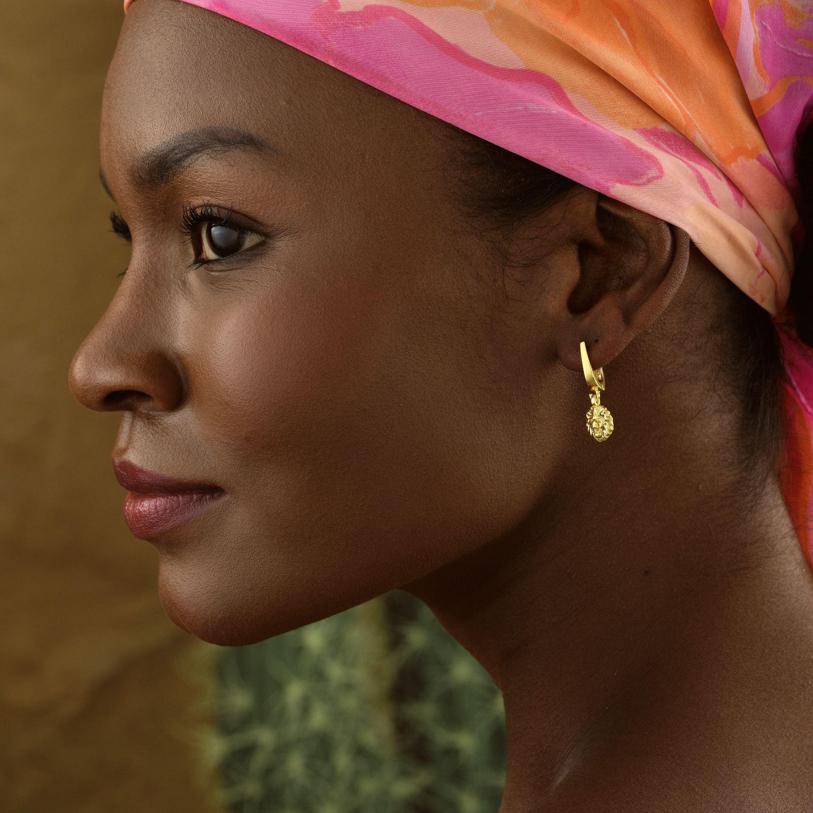 Stylish Lion Dangle Huggie Hoop Earring worn by a model with a colorful headscarf, showcasing its luxurious design.