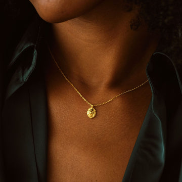 Close-up of a person wearing a Lion Pendant Necklace in gold vermeil against a dark shirt.