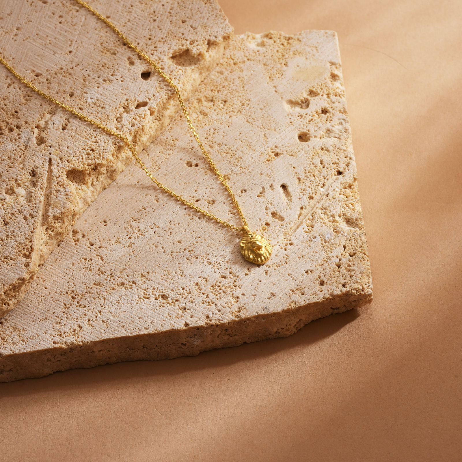 Lion Pendant Necklace in gold vermeil on a textured stone surface