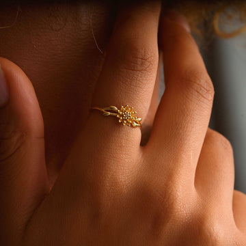 A close-up of a hand wearing a delicate 14K Solid Gold Birth Flower Ring featuring floral design details.