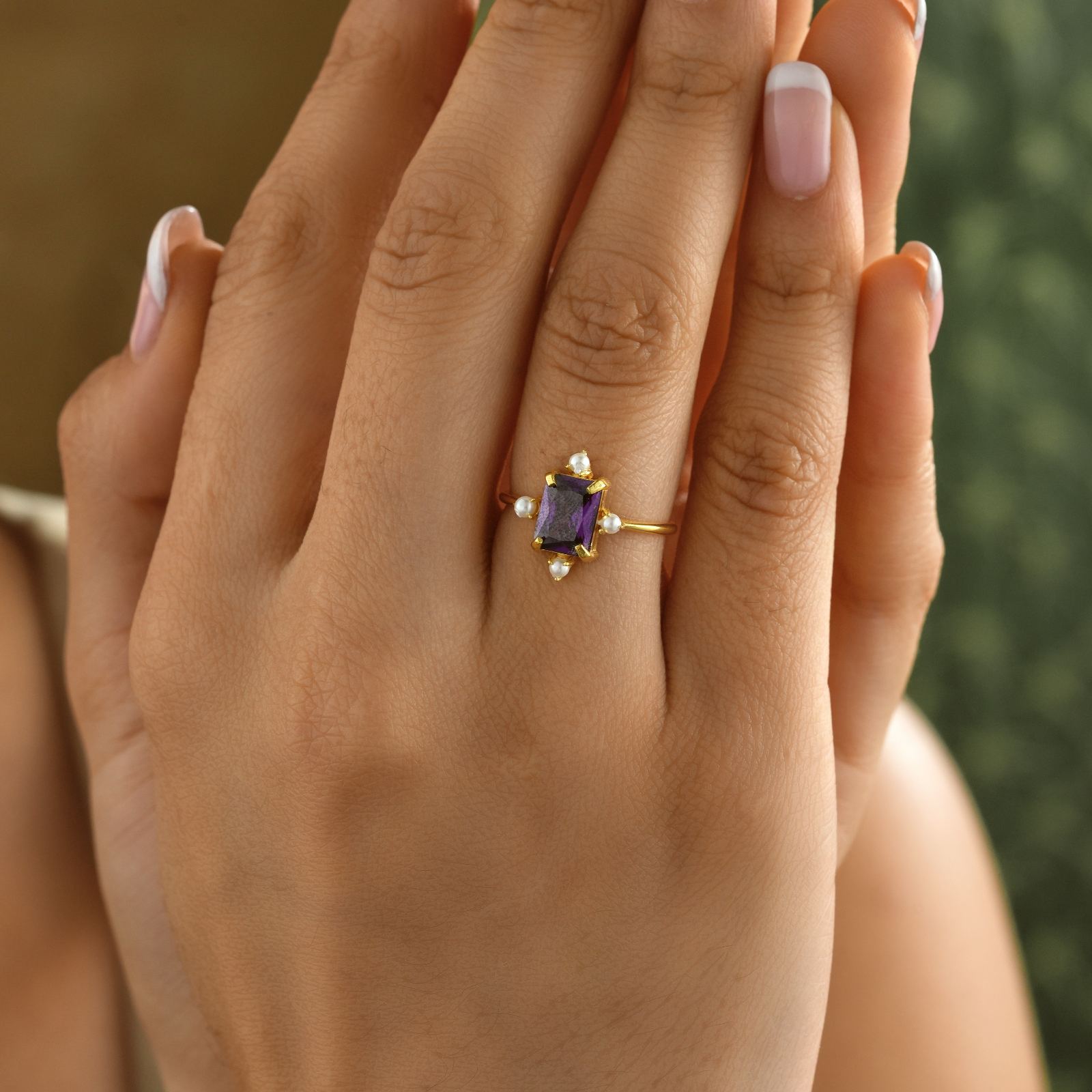 Close-up of a hand wearing a Rectangle Statement Ring with purple amethyst and pearls.