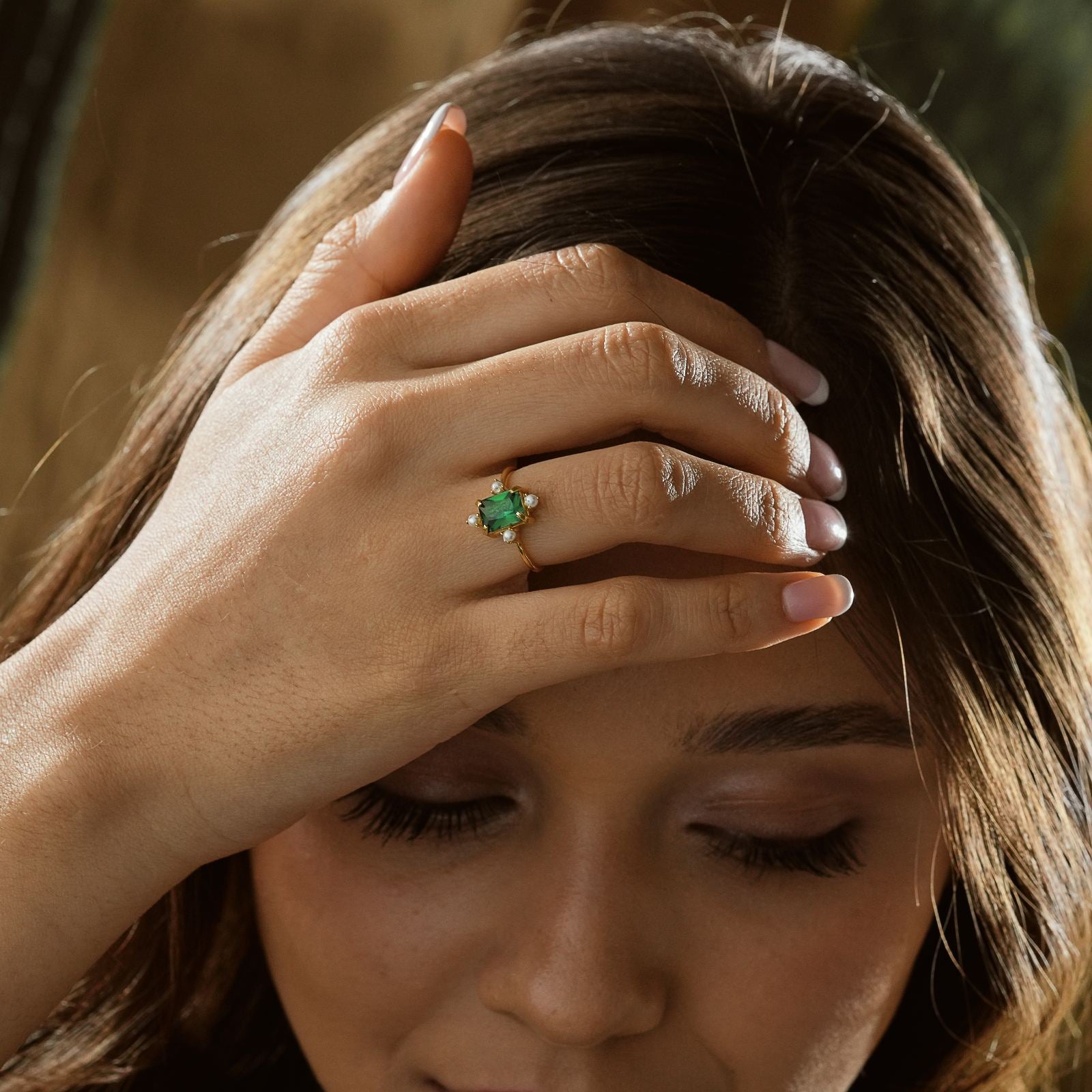 Woman wearing a Rectangle Statement Ring with a green gemstone, showcasing elegance and style.