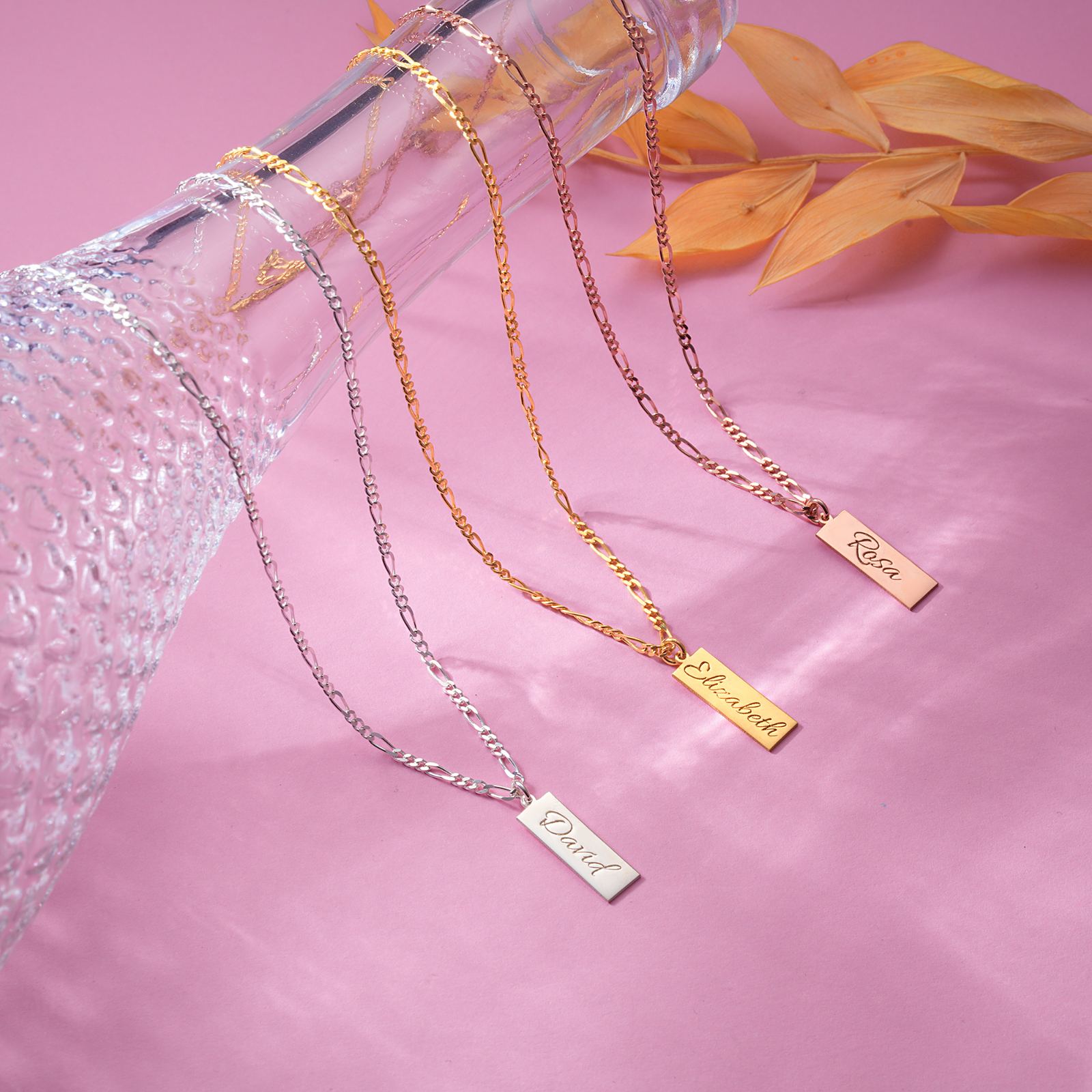 Bar Name Necklace Sterling Silver displayed with personalized names on a vibrant pink background.