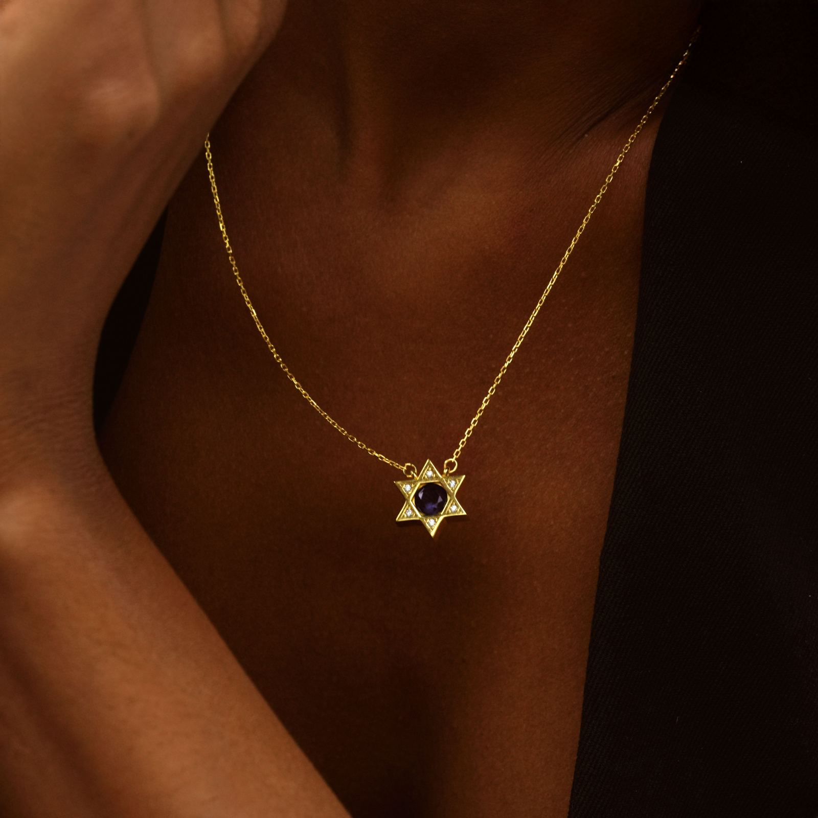 Star of David Necklace Elegant Silver on a gold chain, worn stylishly against a dark background.