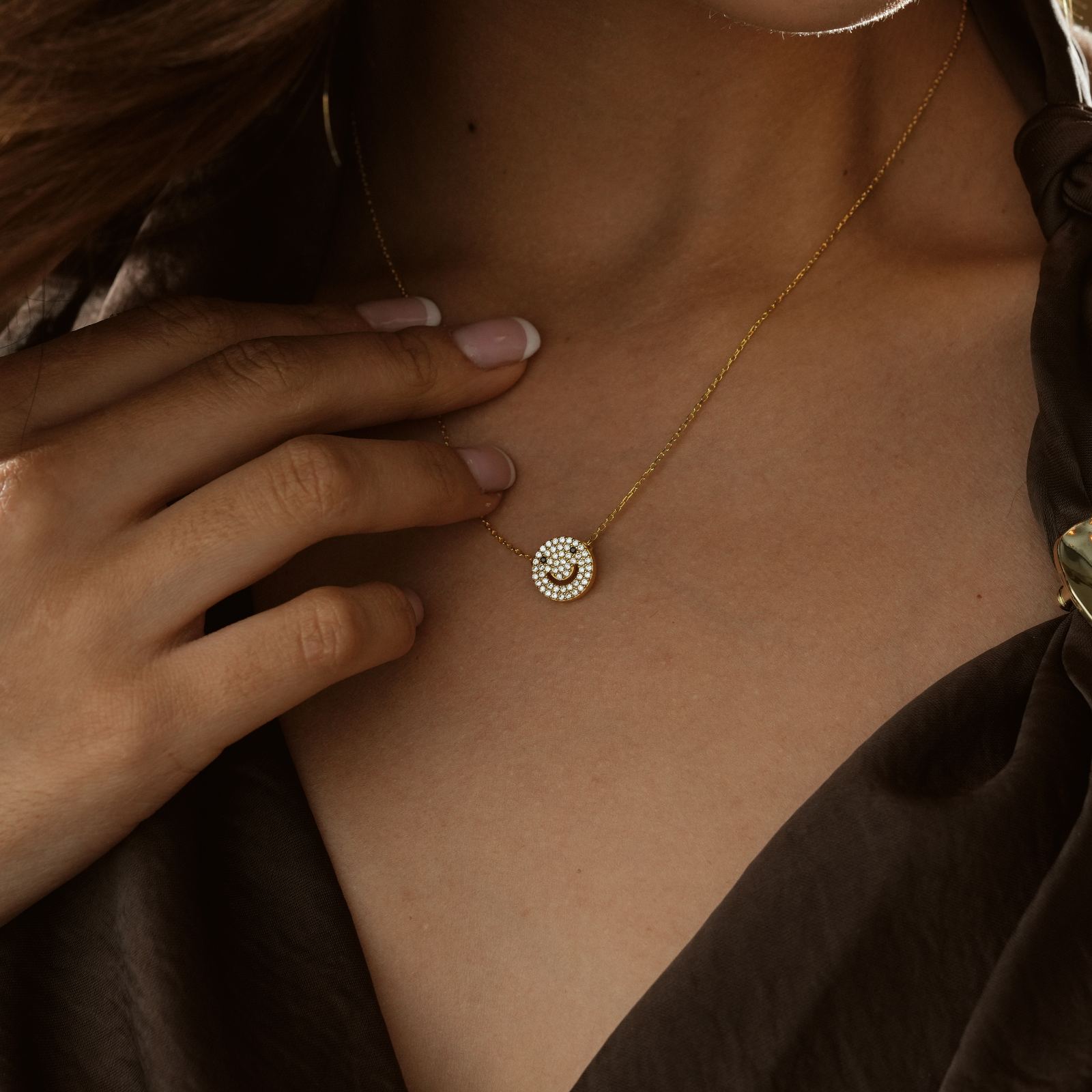 Charming Dainty Smiley Face Necklace worn on a model with a hand touching the pendant, showcasing its elegance.