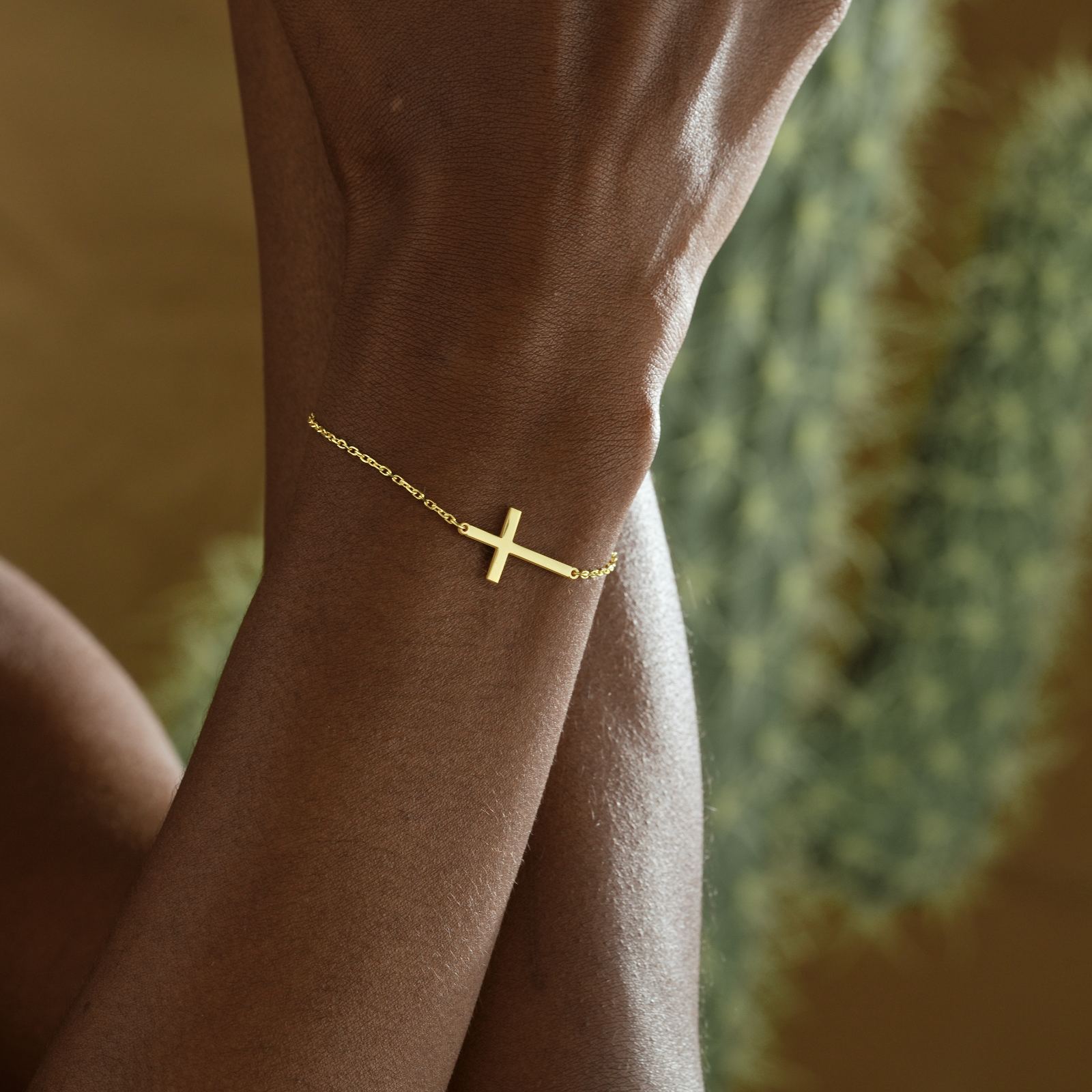 Elegant Sterling Silver Cross Bracelet worn on a wrist, featuring a delicate cross design in gold.