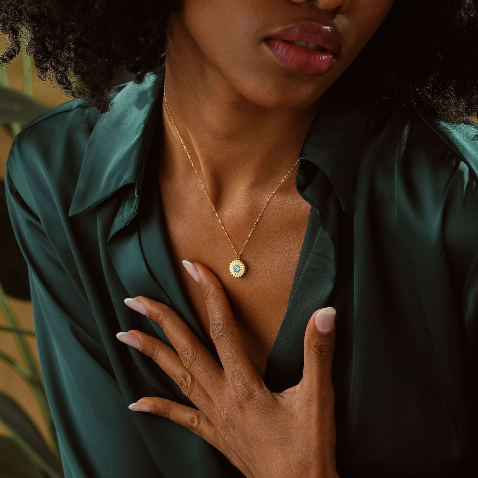 Woman wearing a Charming Sunflower Birthstone Necklace against a green blouse background.
