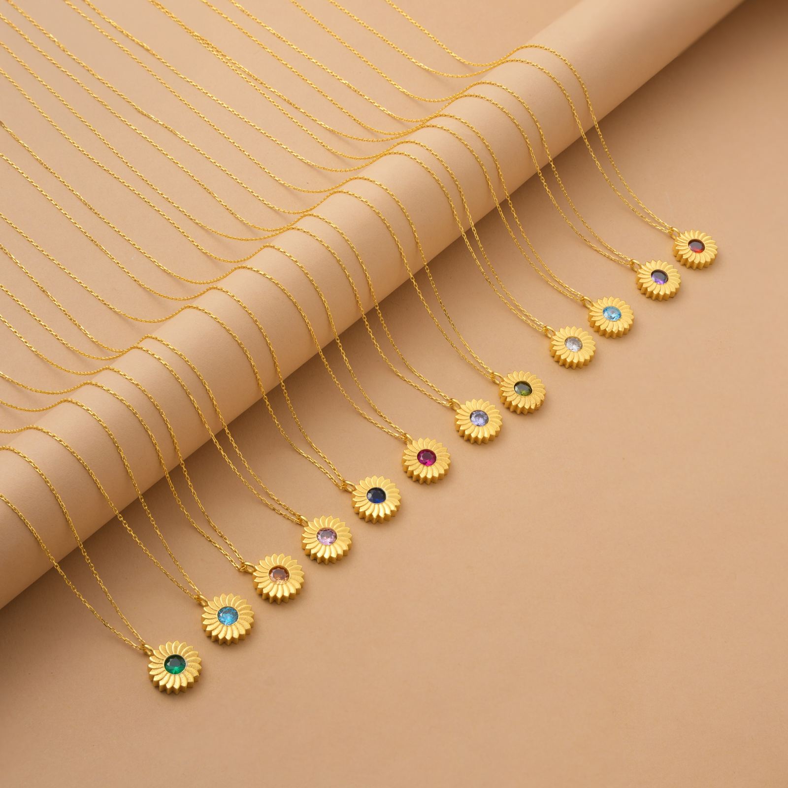 Charming Sunflower Birthstone Necklace in various colors displayed on a golden background.