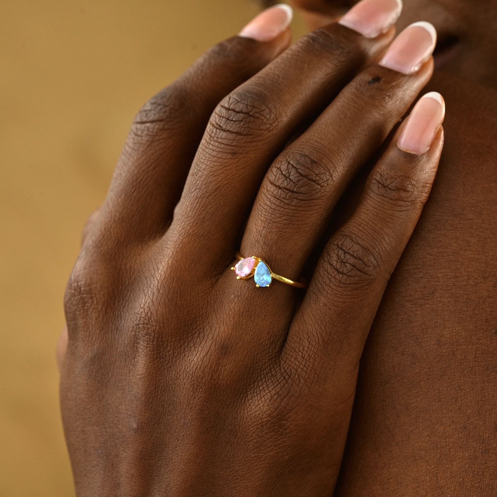 Teardrop Heart Birthstone Ring displayed on a hand with gold finish, featuring pink and blue gemstones.