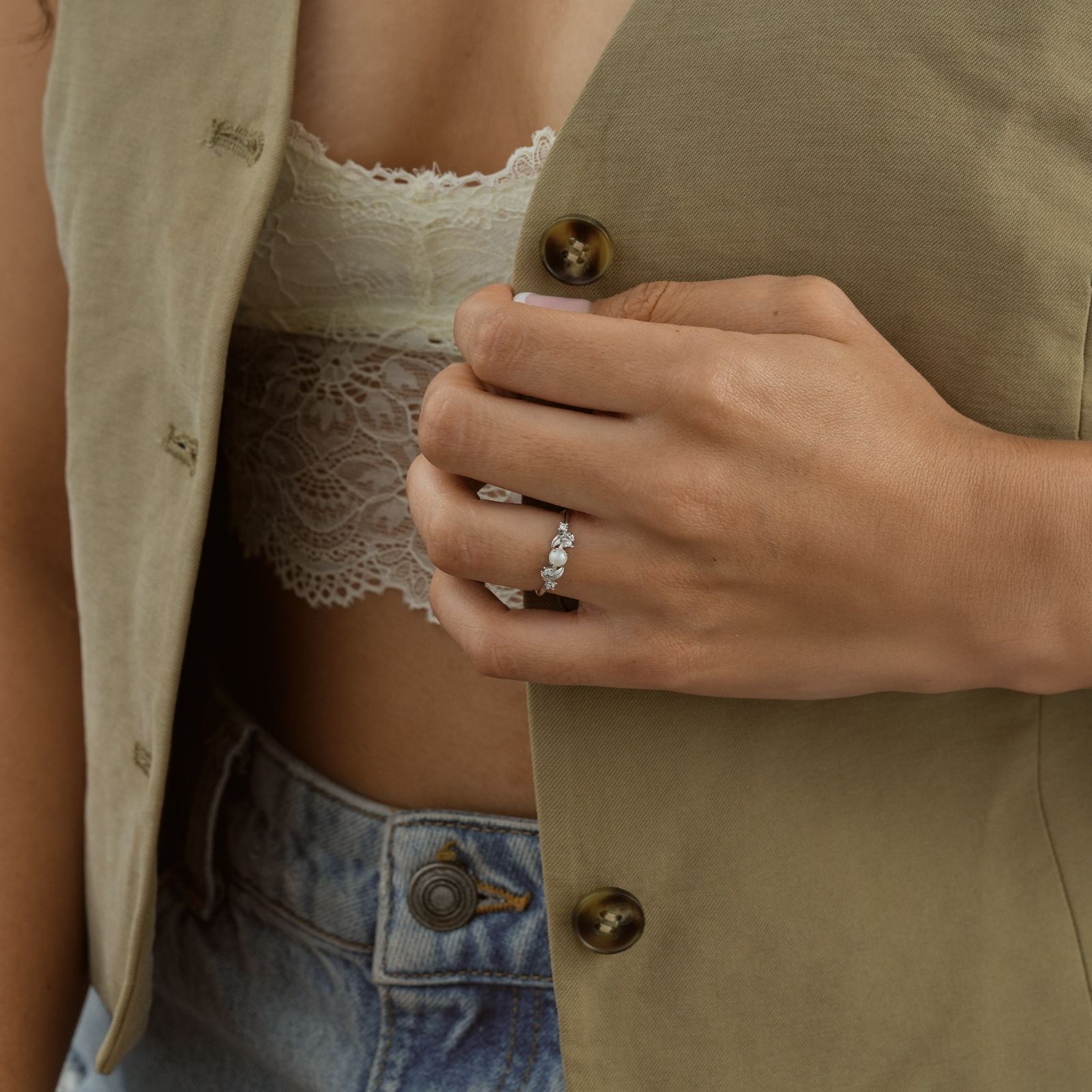 Close-up of a hand wearing a Vintage Pearl Engagement Ring, showcasing detailed design with silver accents.
