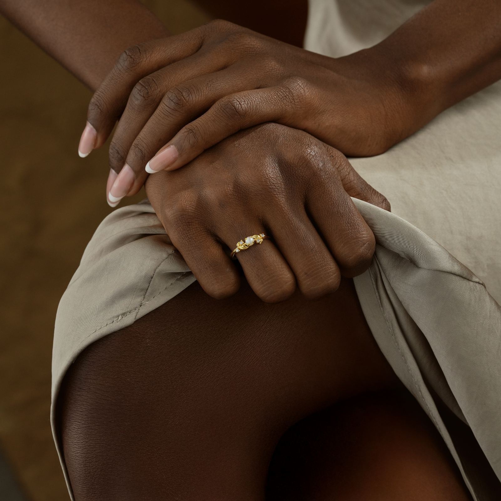 Model showcasing a Vintage Pearl Engagement Ring on her hand, wearing a stylish beige dress.